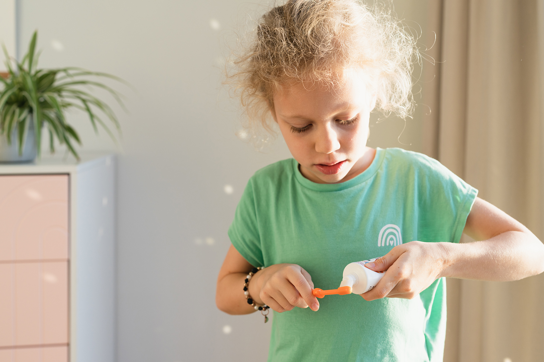 A child puts toothpaste on a toothbrush