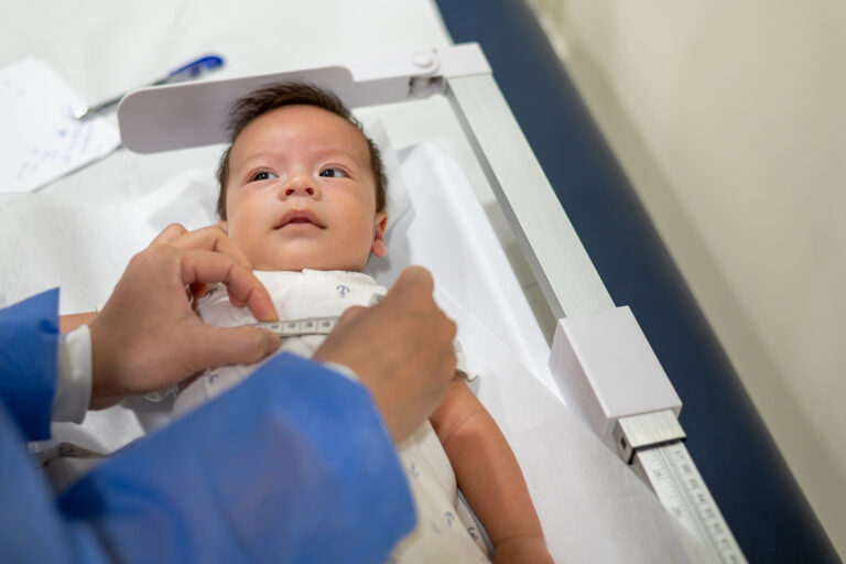 A newborn baby being measured around its tummy