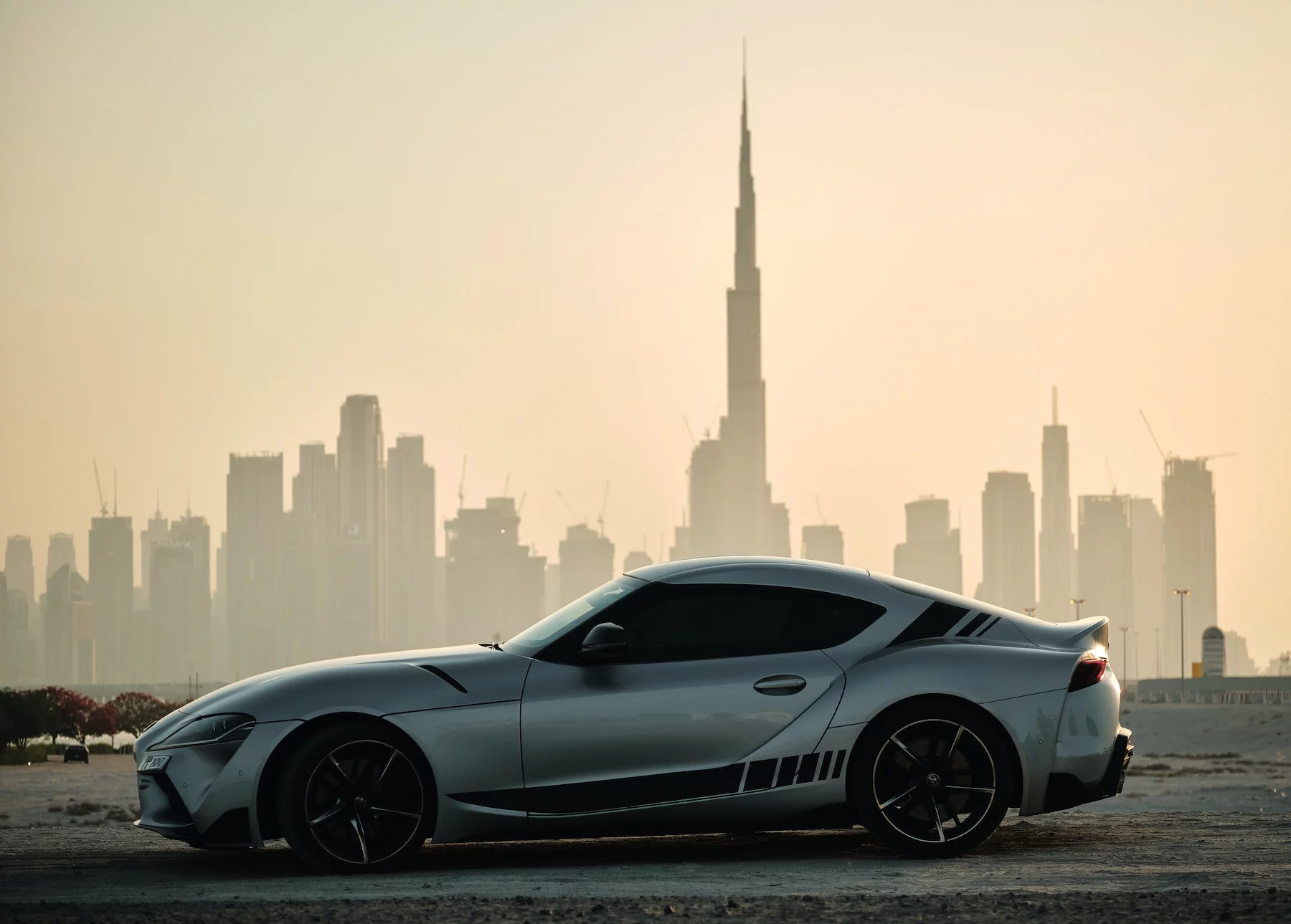 sports car parked in front of Dubai skyline