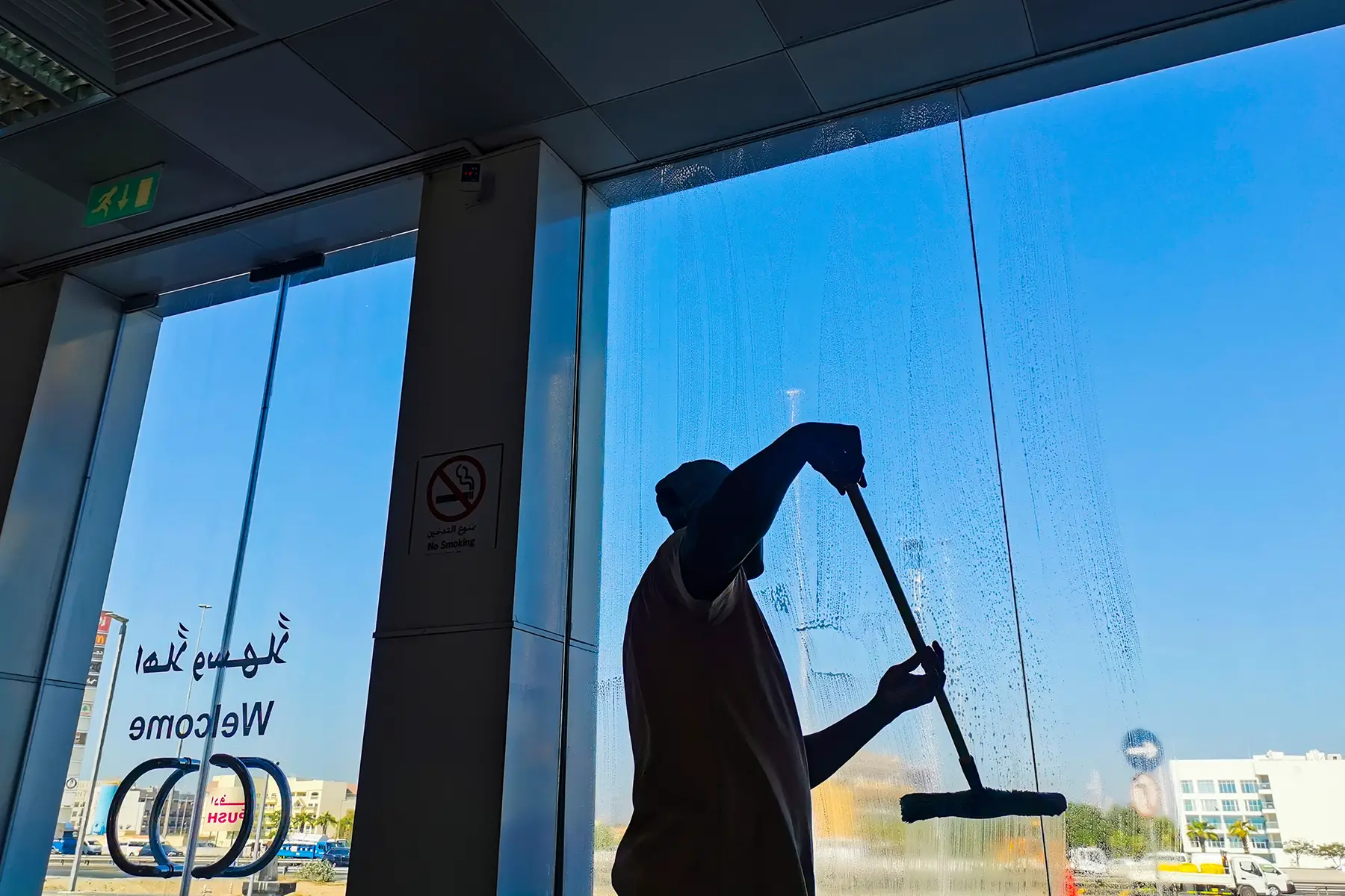A worker cleaning a window with a wet brush