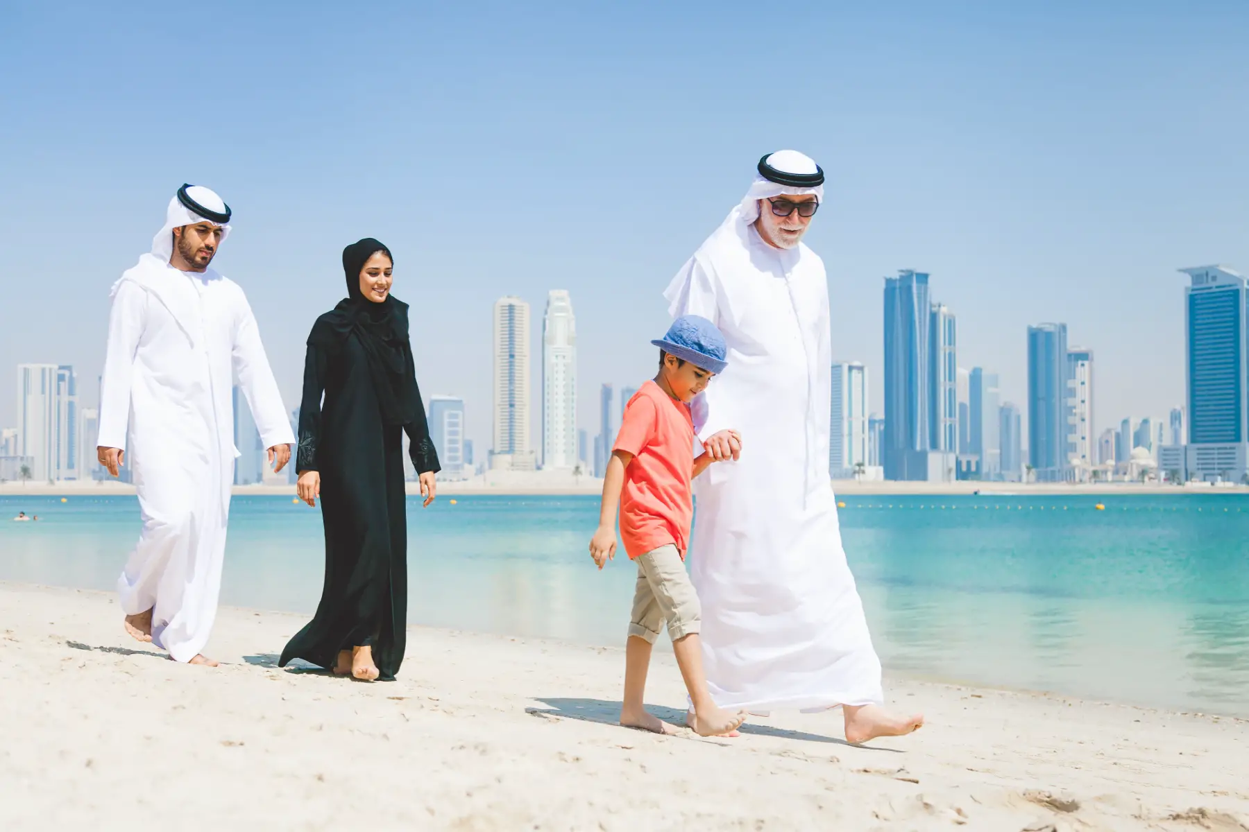 Emirati family with young boy walking on beach in Dubai, UAE