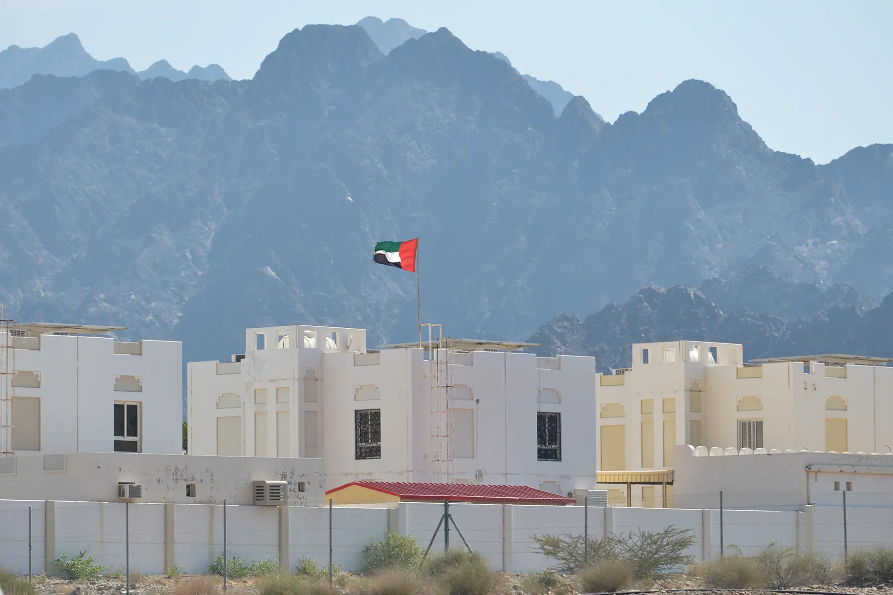 Houses in front of mountains with a UAE flag flying from the roof