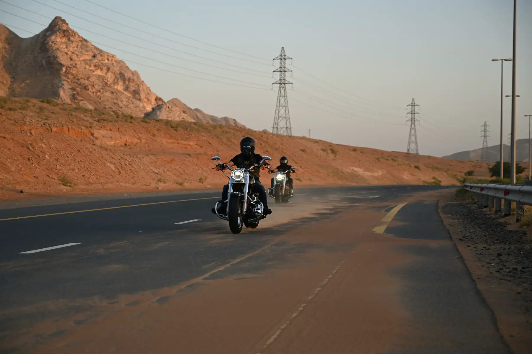 Two motorcyclists driving on a highway in the UAE.