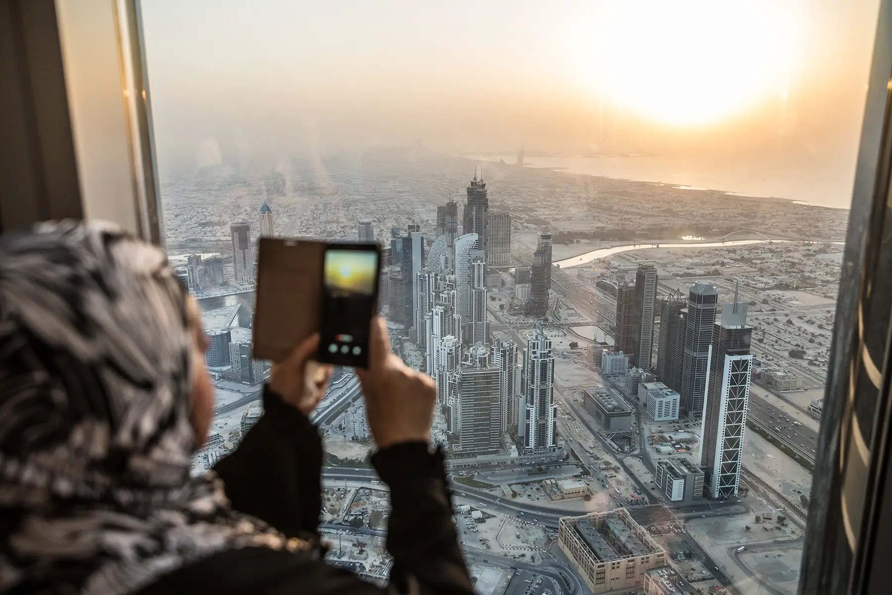 Woman taking a photo of Dubai with her mobile phone