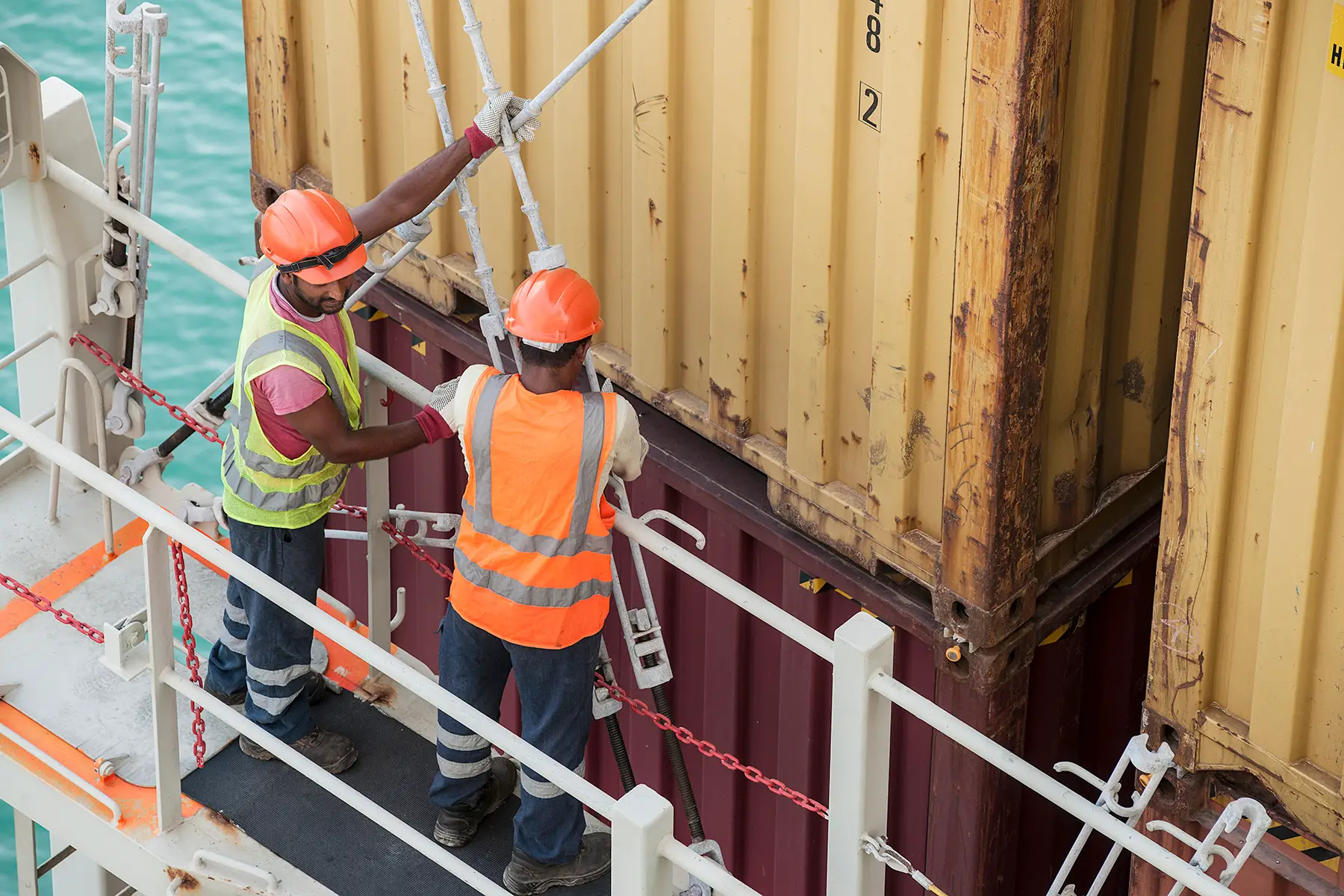 Two workers handling shipping containers