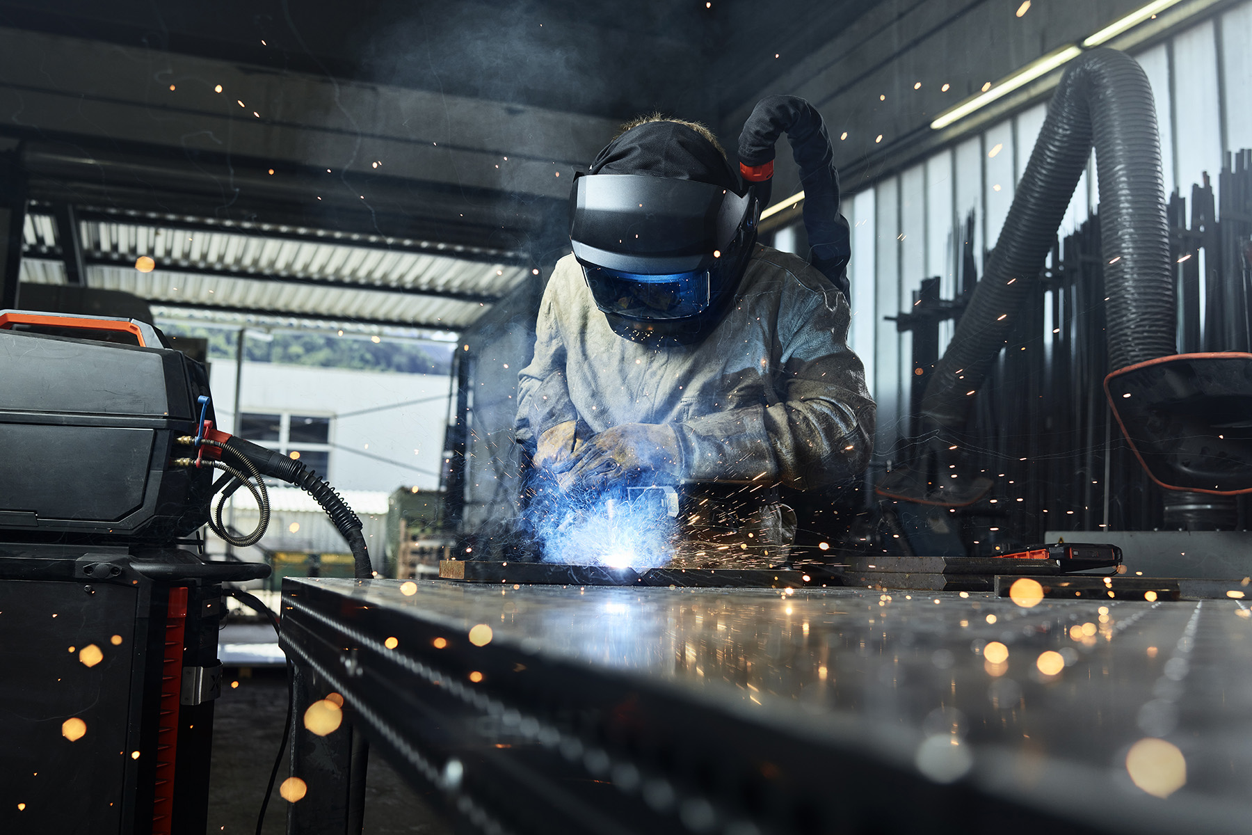 A metal worker wearing protective gear welds something