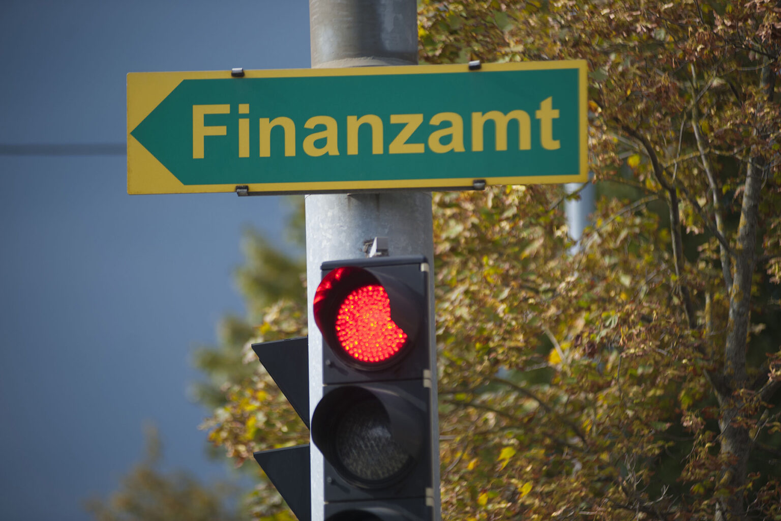 A road sign on a red traffic light pointing to an Austrian tax office (German: Finanzamt)