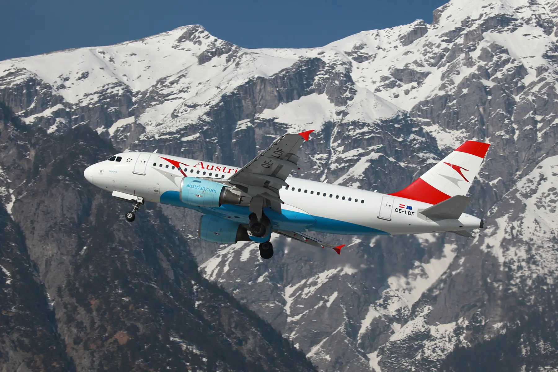 An Austrian Airlines airplane taking off from Innsbruck Airport against a mountain backdrop