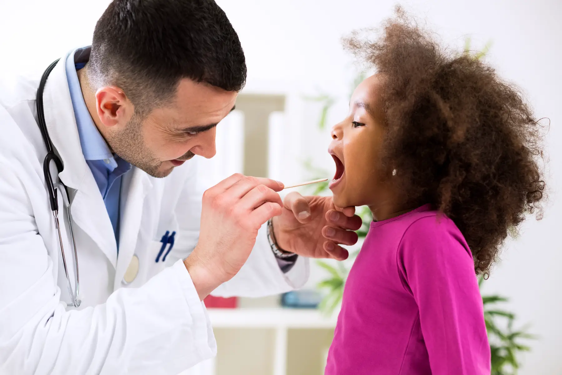 Doctor checking child's throat