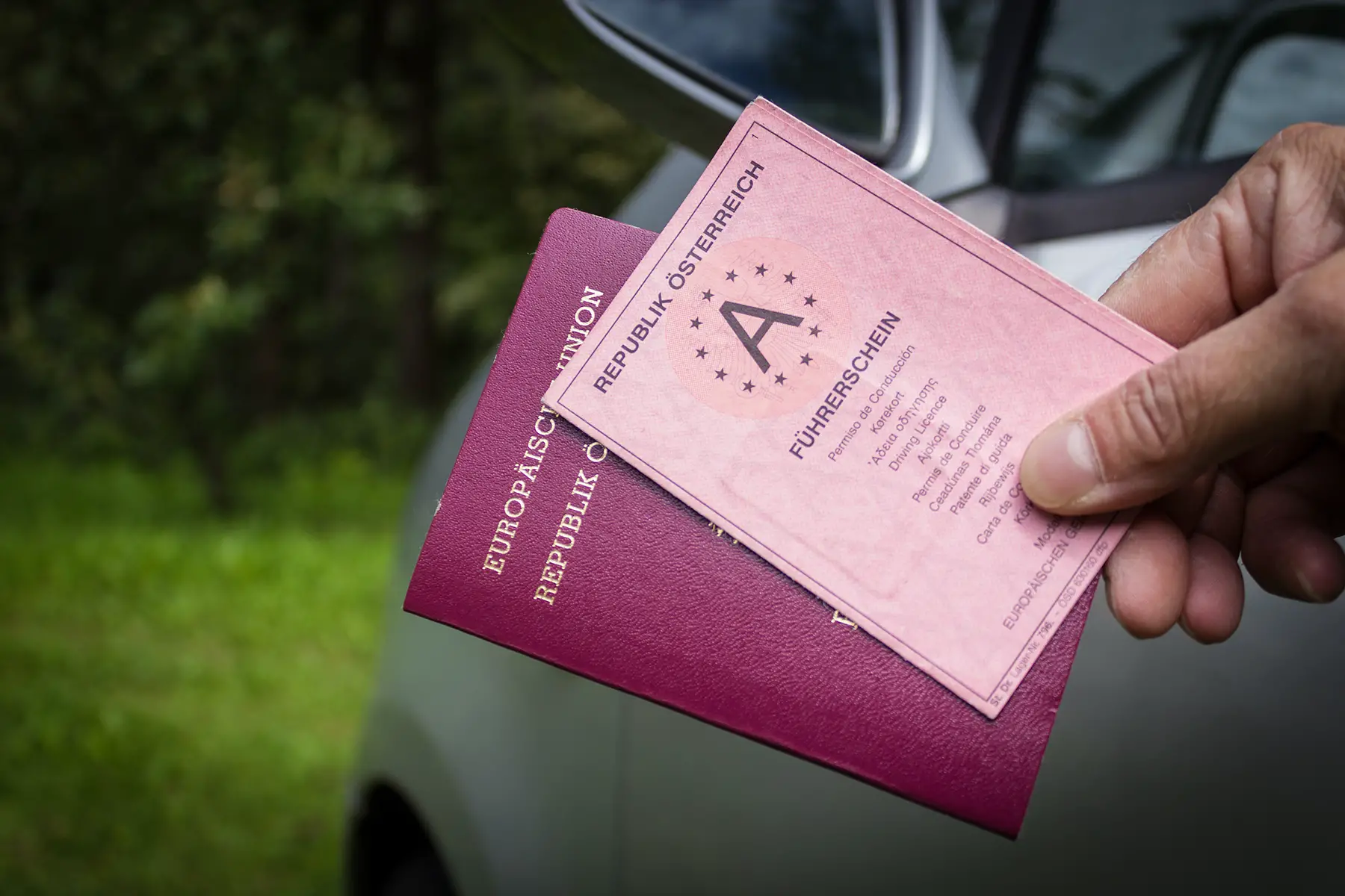A man holding his Austrian driving license and his passport