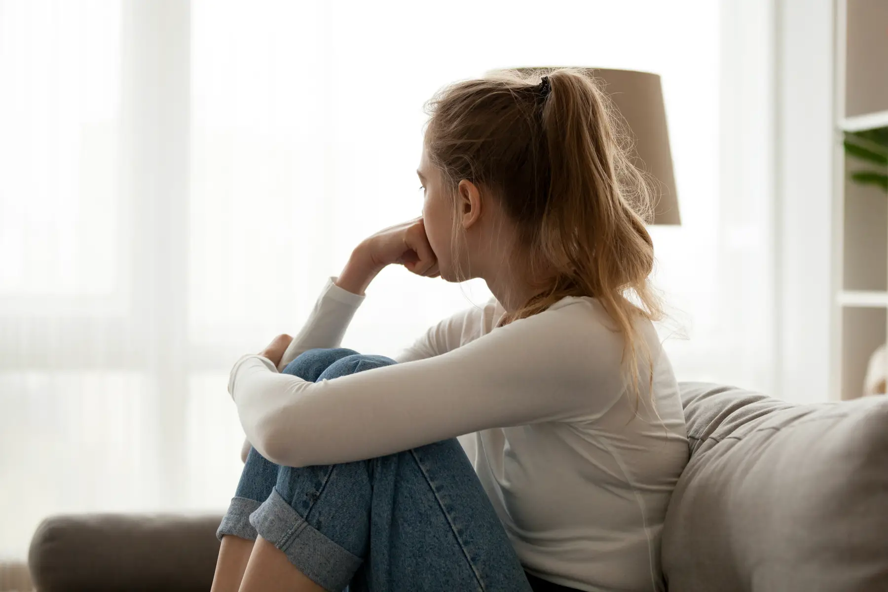 Pensive woman sitting on a couch