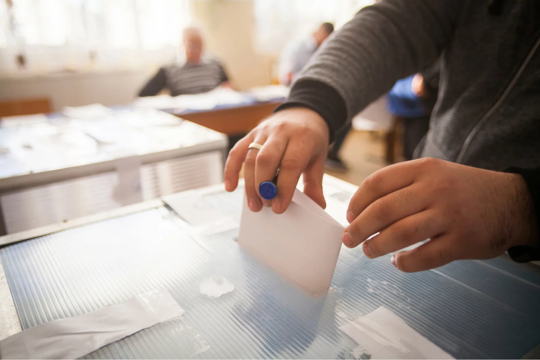 Voter placing a ballot inside of a ballot box