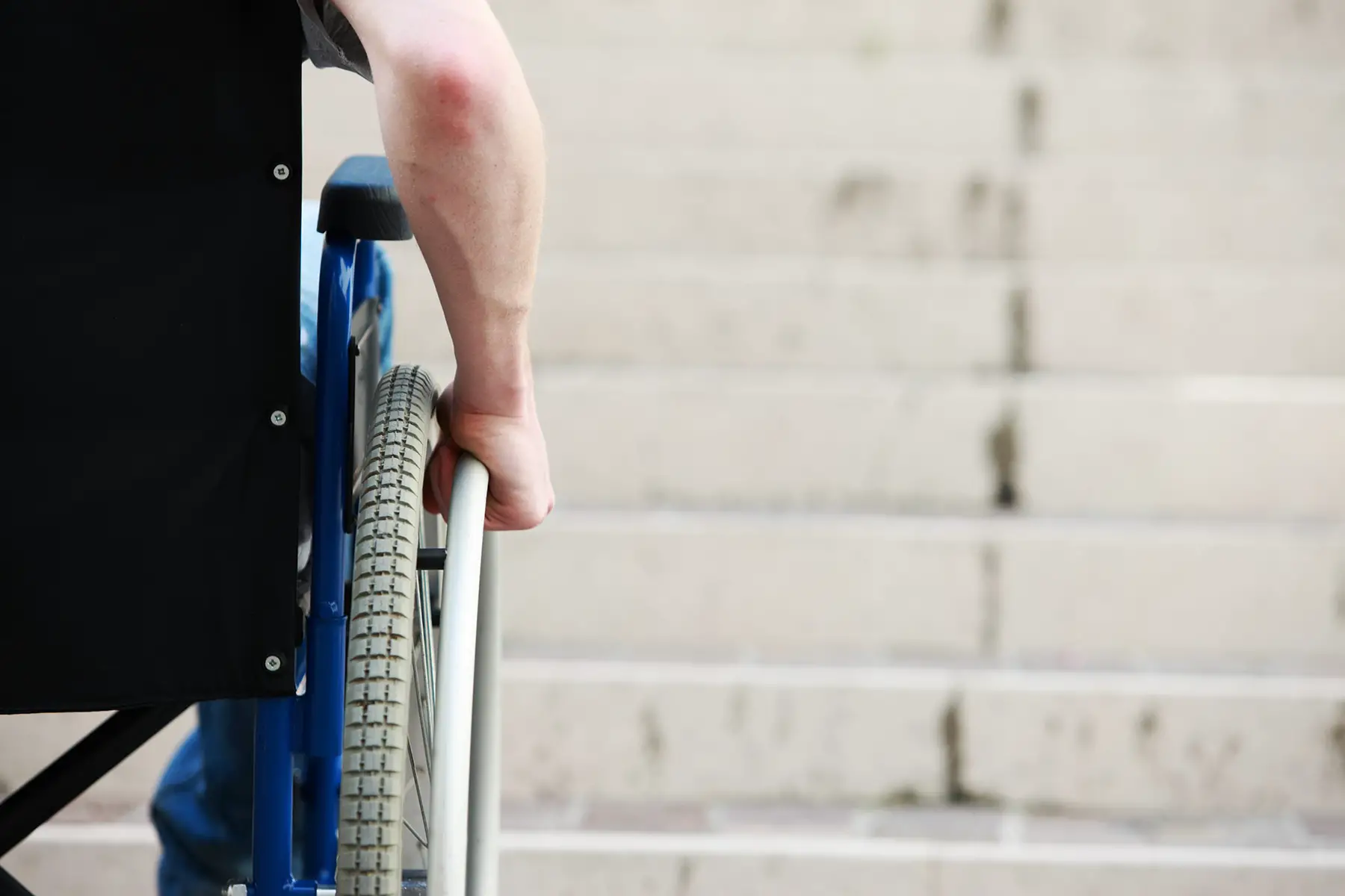 Wheelchair user in front of a set of stairs
