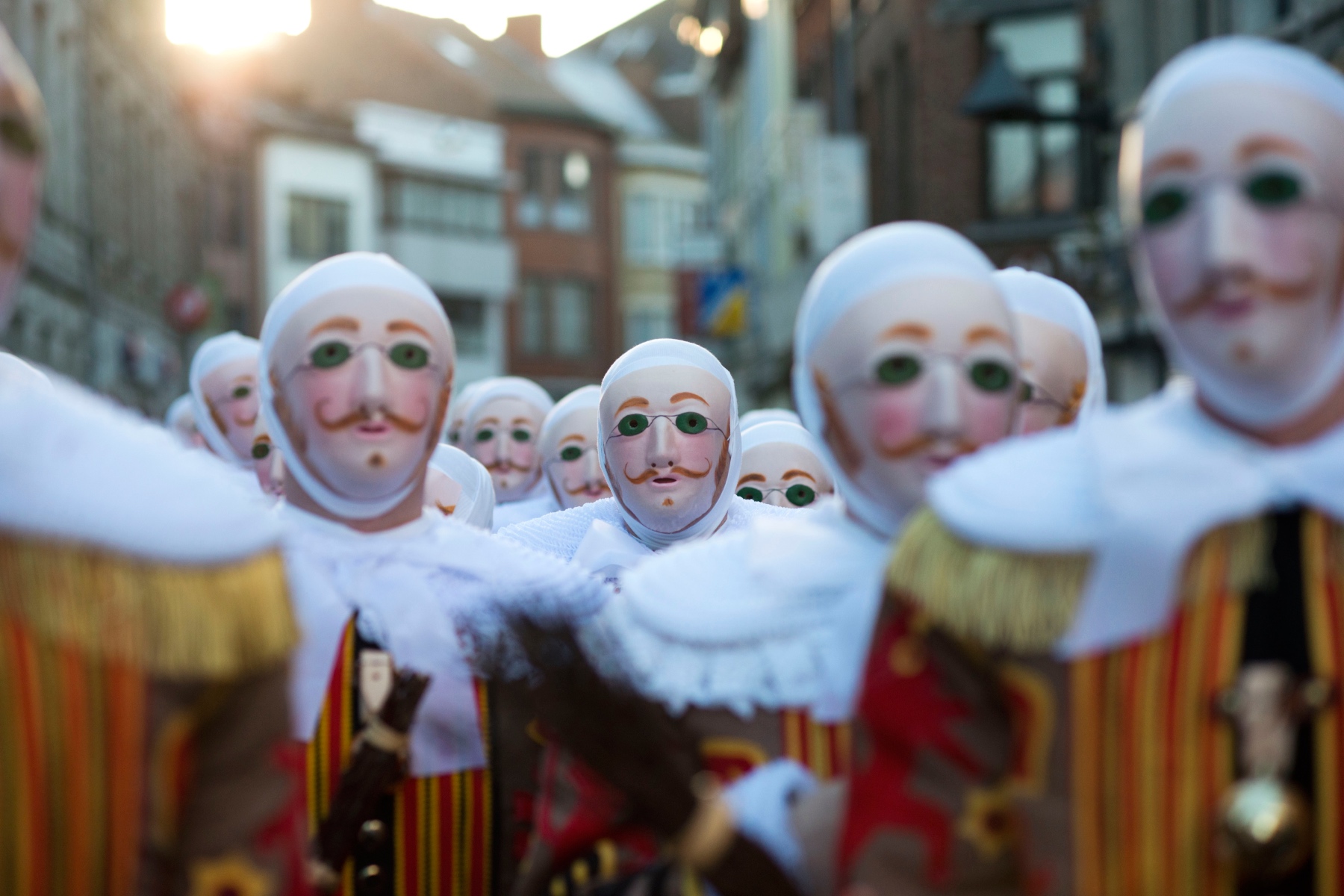 Men wearing traditional masks and costumes stands together during Carnaval de Binche celebrations in Brussels