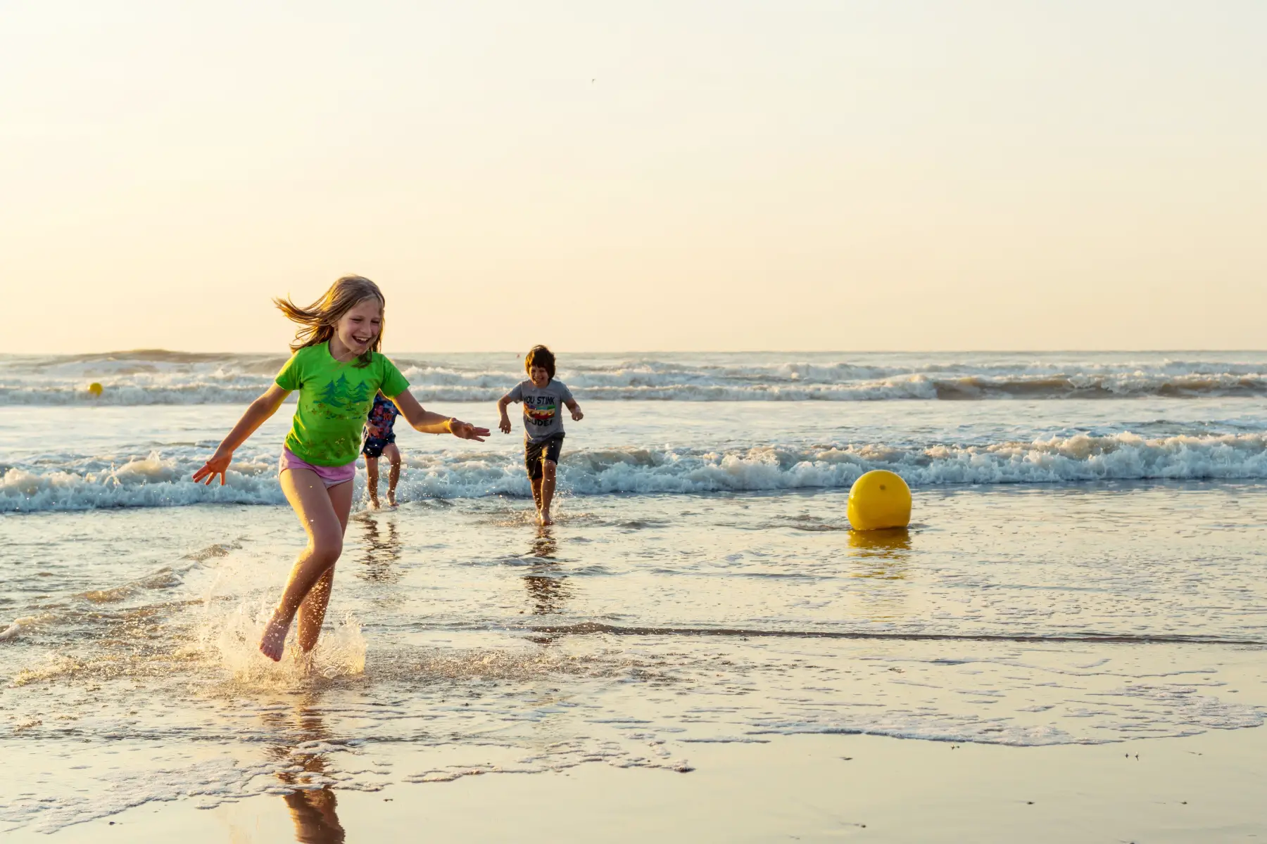 A girl and a boy run on the shore of Bredene aan Zee beach