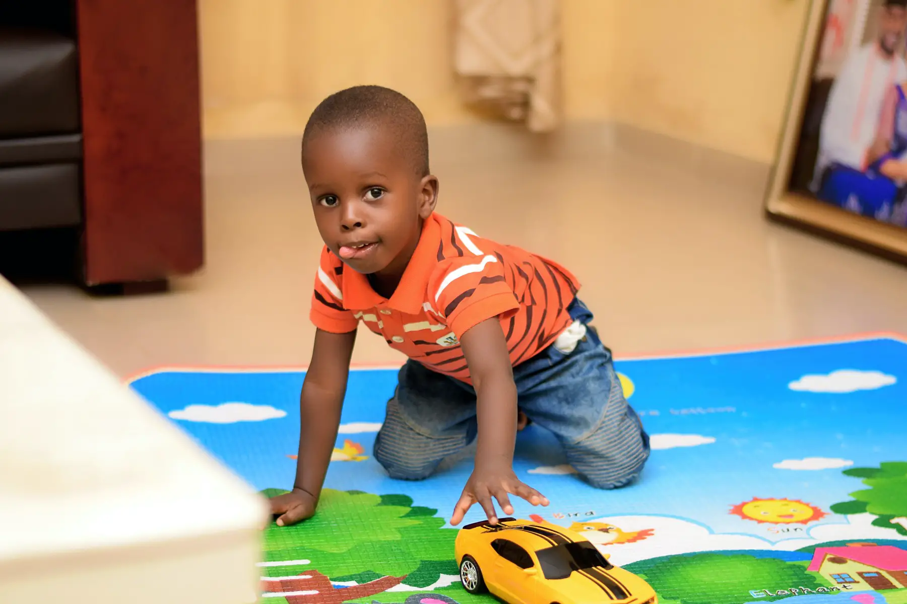 Little boy playing with a toy car at his childminder's home.