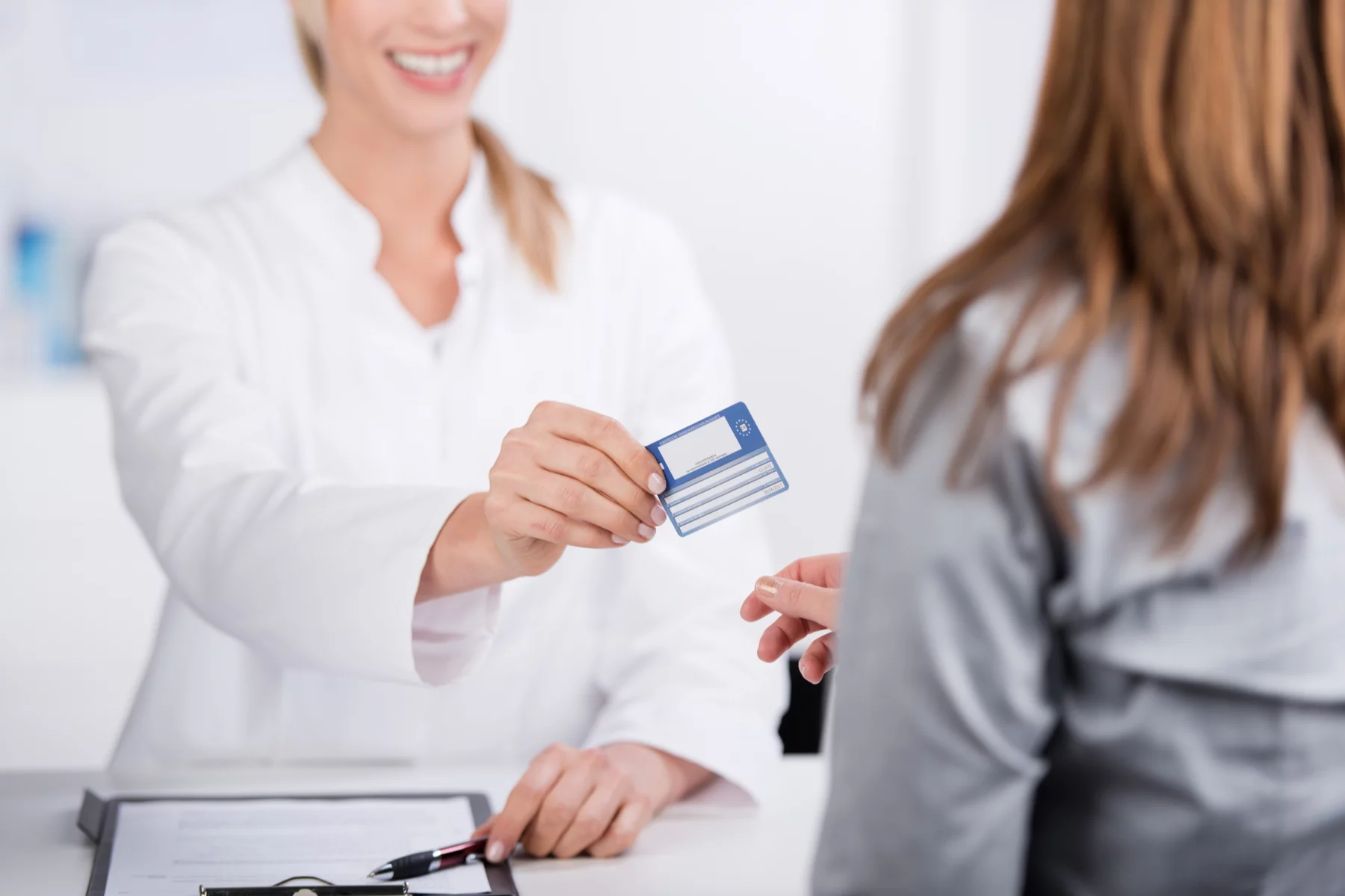 a doctor handing a patient their European Health Insurance Card