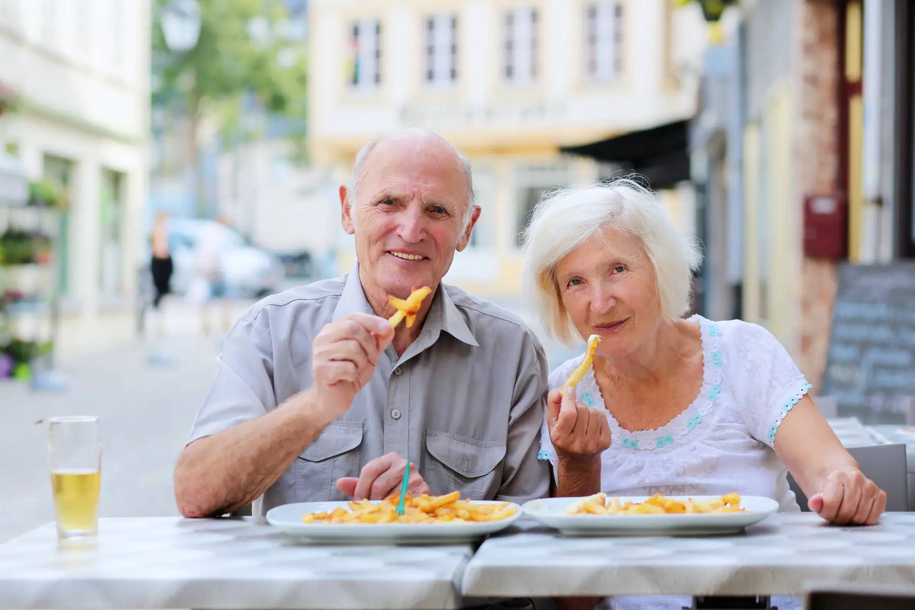elderly couple eating belgian fries at a cafe