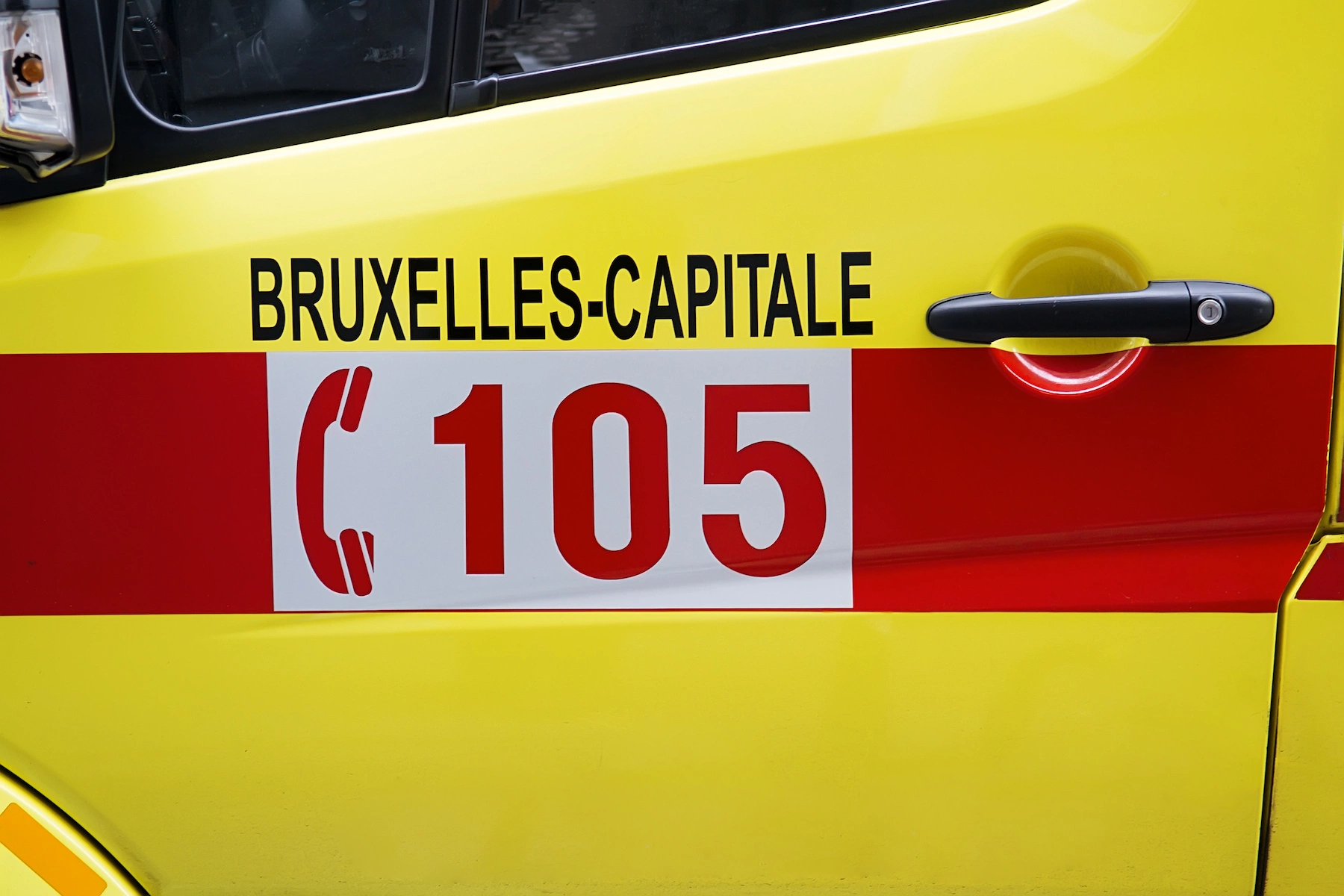 An emergency number for Belgium is displayed on the drivers side door of an ambulance