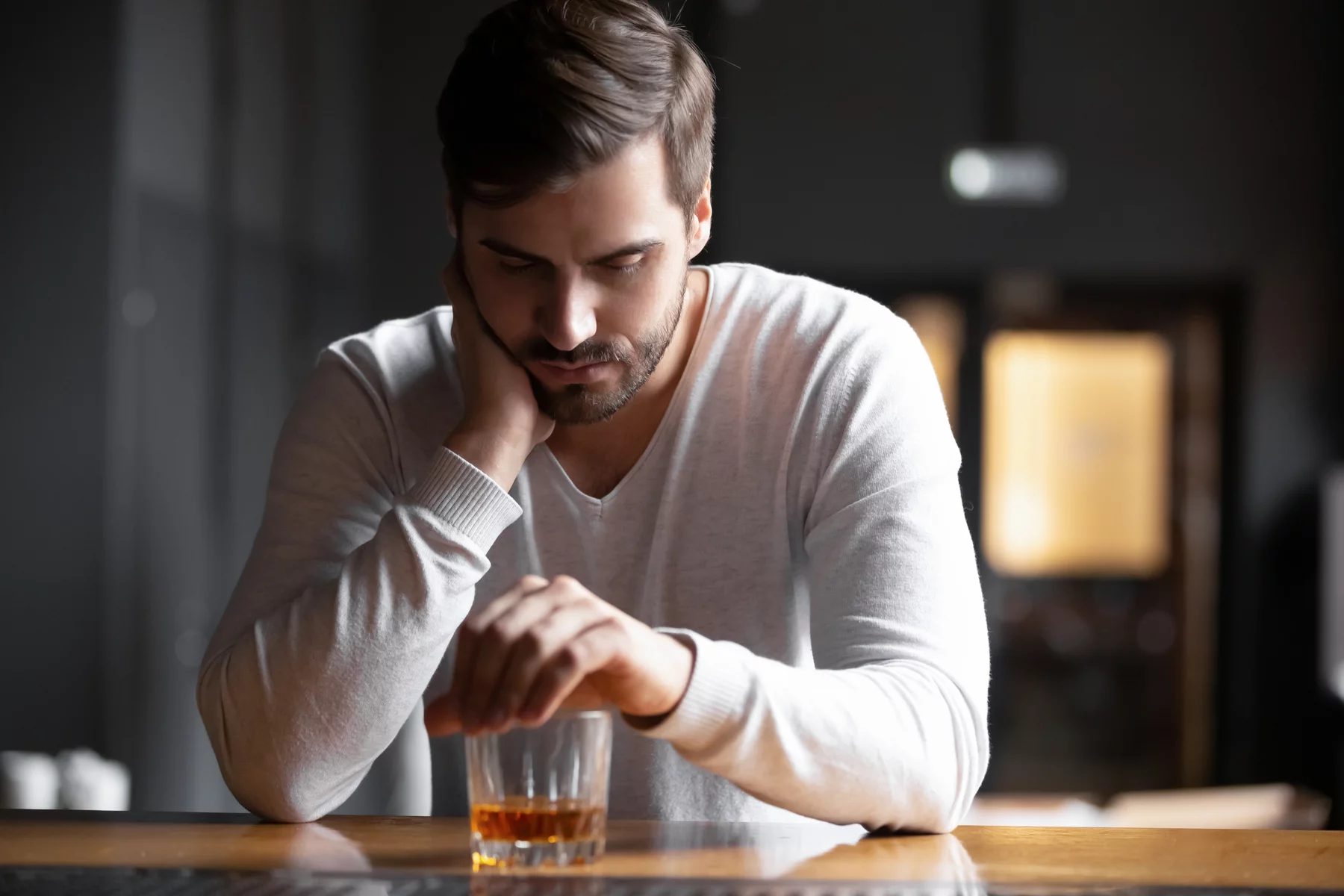 man sitting alone at table with whisky glass