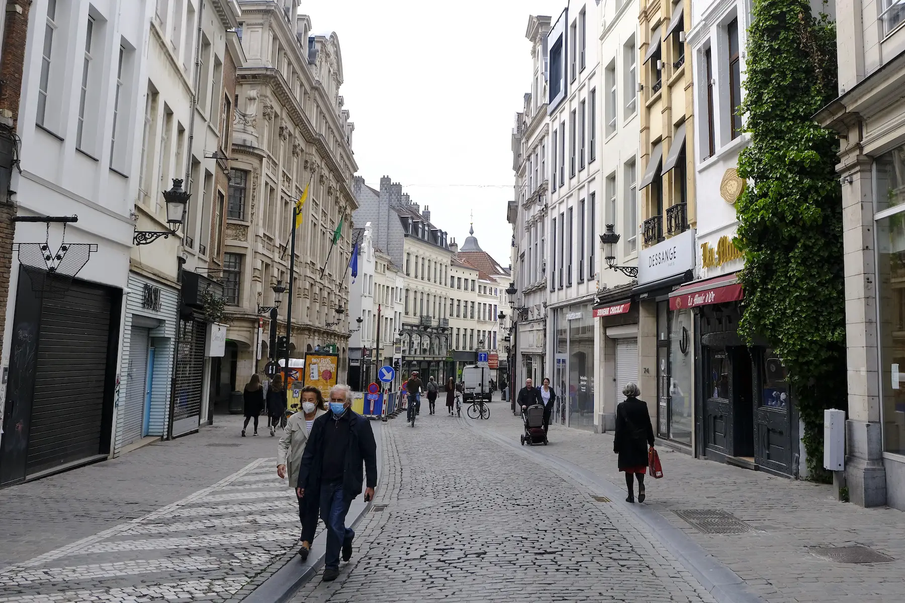 Residents wearing face masks walk along a closed shopping street in Brussels, Belgium during COVID-19 lockdown
