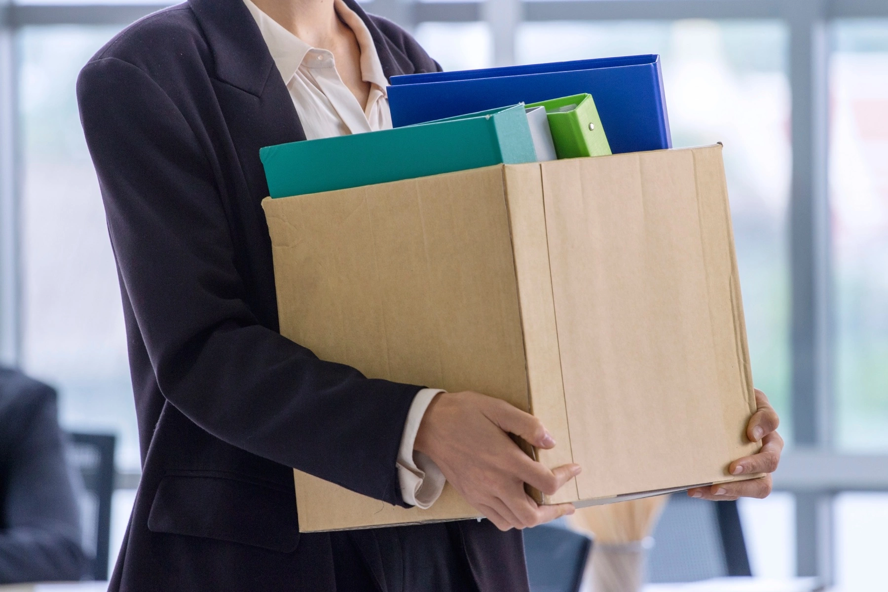 an employee in a suit carrying a box full of work files