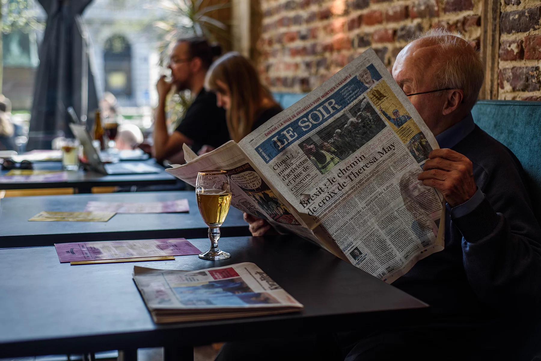 Man in a Brussels café reading the newspaper over a beer