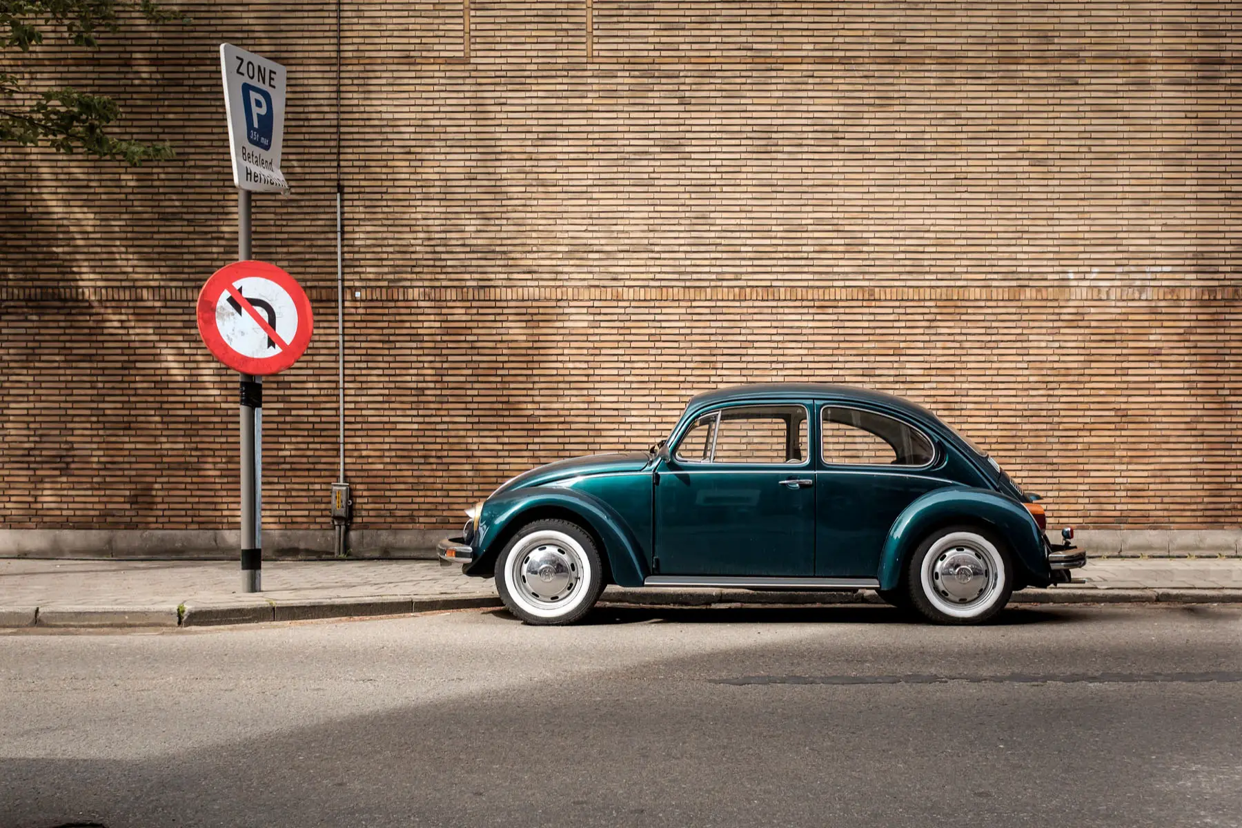 a vintage VW Beetle parked near road signs in Antwerp, Belgium