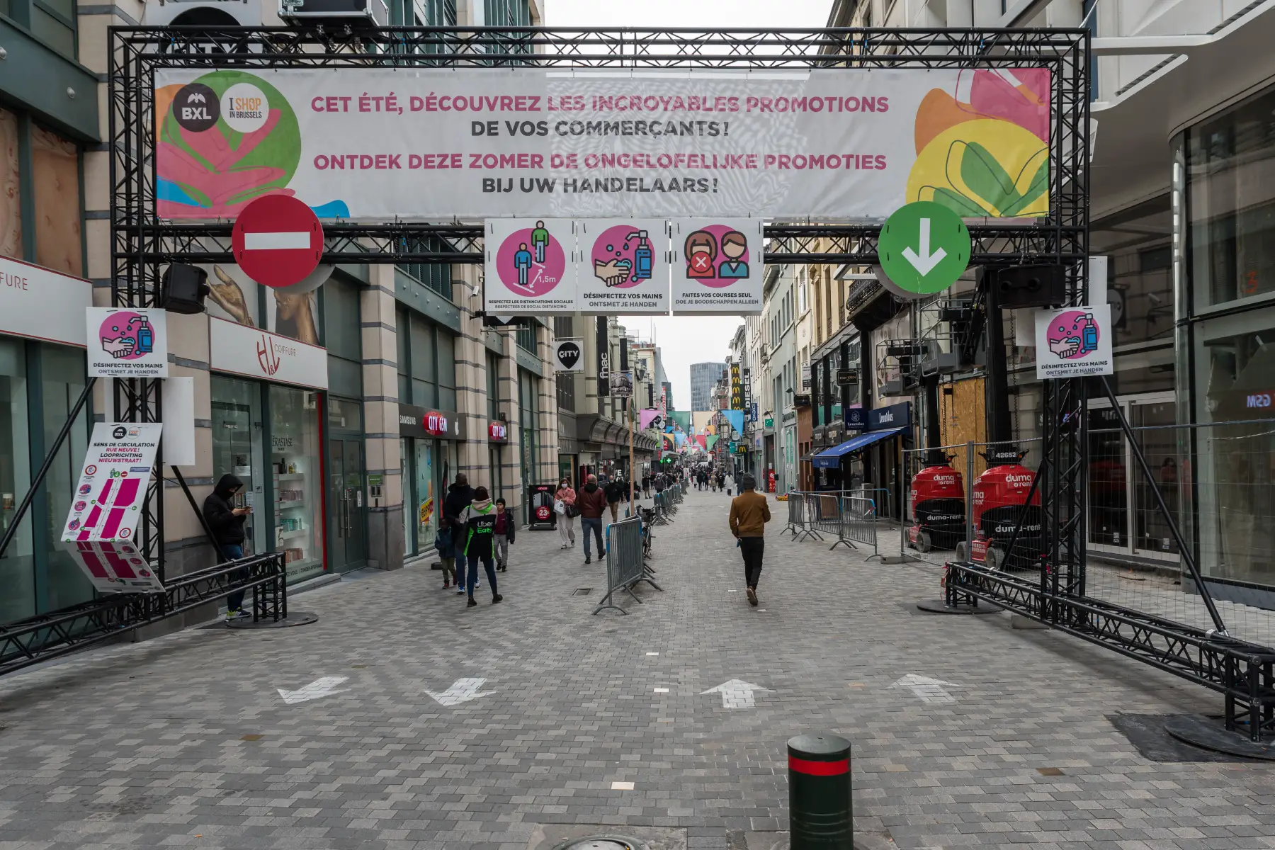 A shopping street in Brussels with a large archway and a sign telling people to walk on the right-hand side.