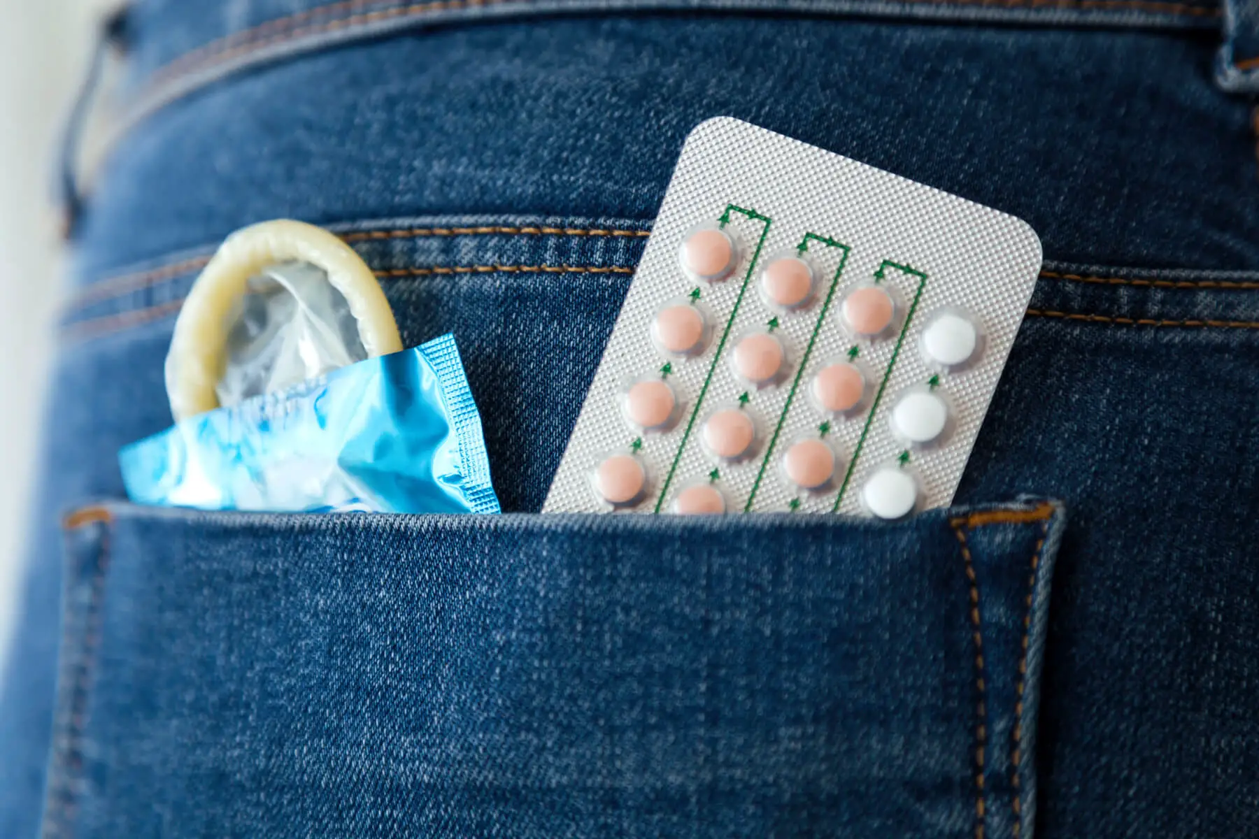 a woman's pocket filled with birth control pills and condoms