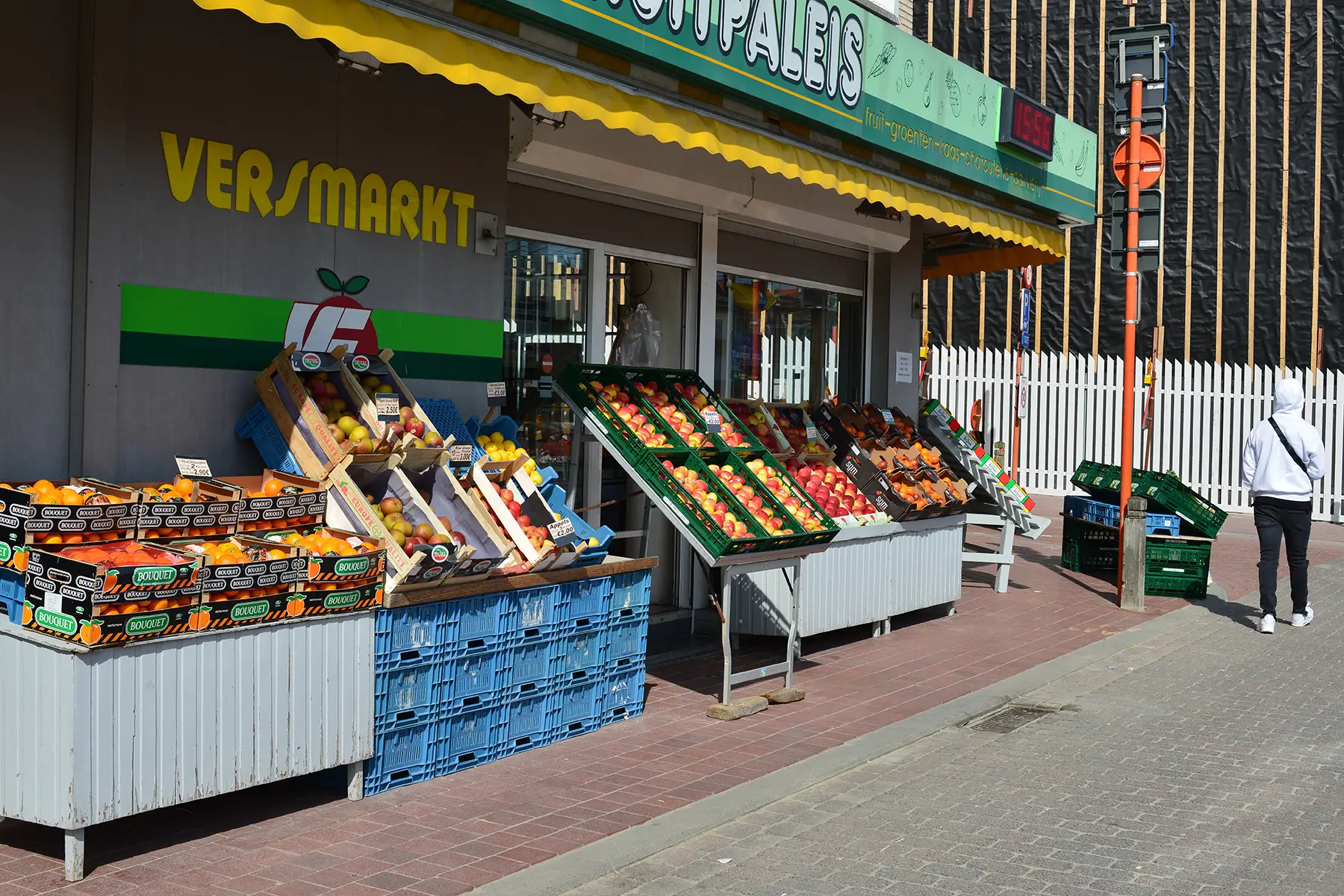 Pedestrian walks past open fresh produce stalls outside Fruit Palace, a supermarket in West-Vlaanderen