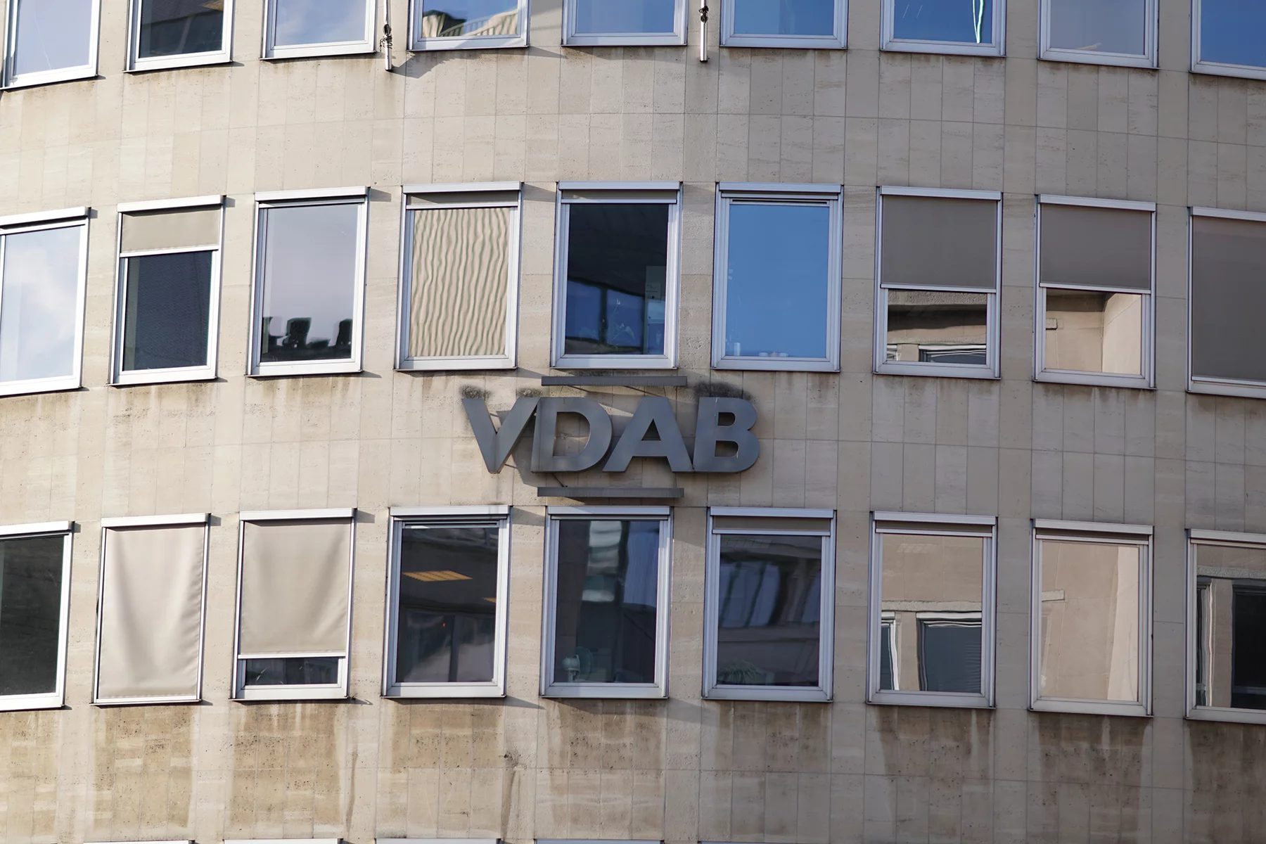 A close-up of a modern, beige building with the sign 'VDAB'