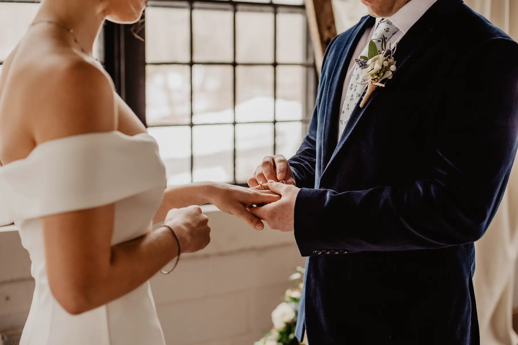 Groom places wedding ring on bride's finger during wedding ceremony