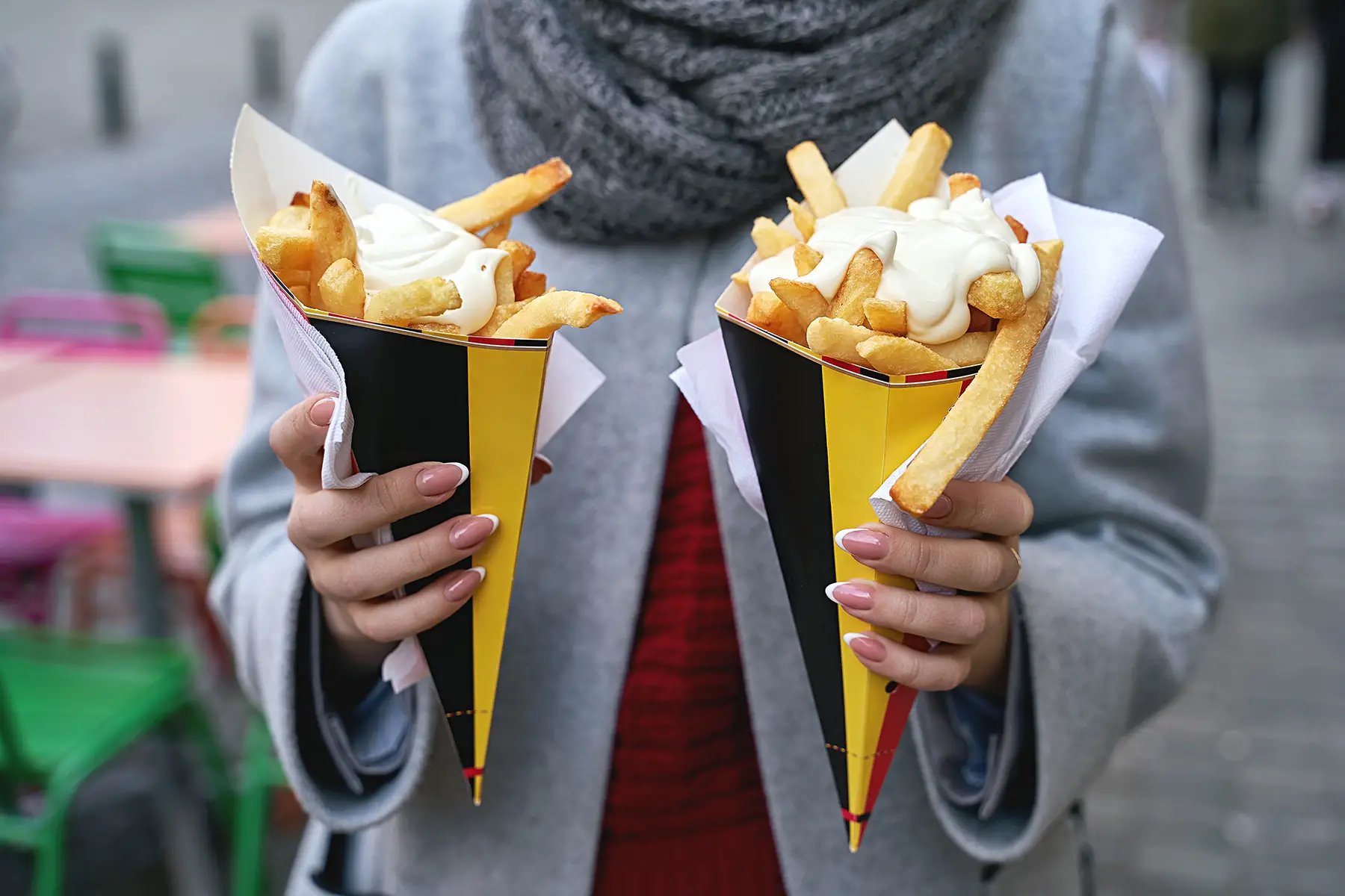 Woman holding two cones of Belgian fries