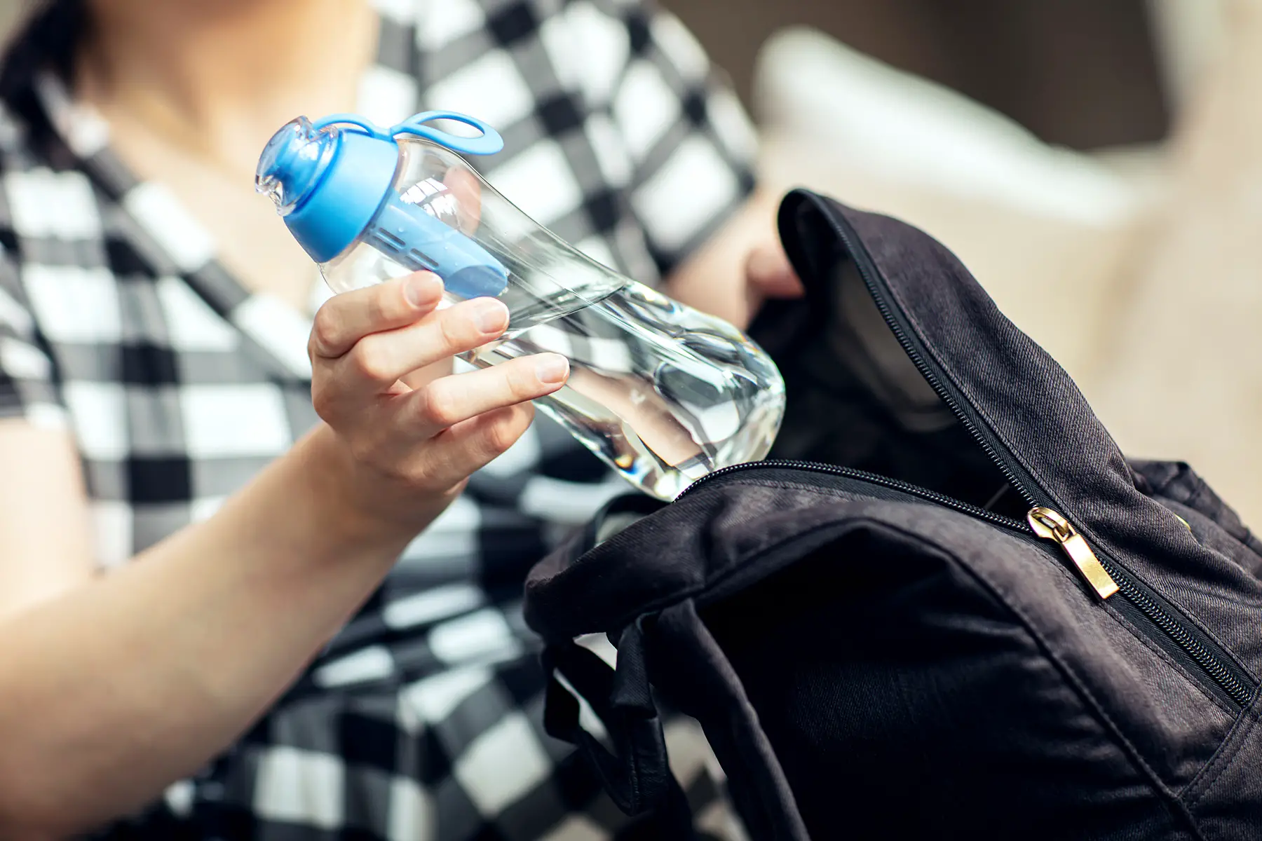 Woman putting a water bottle in her backpack