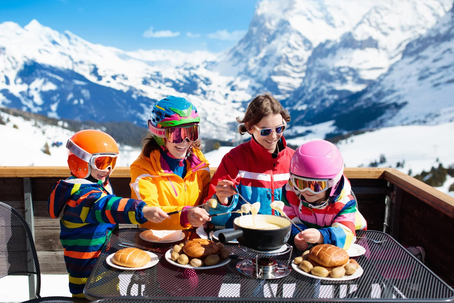 family with young children shares fondue on a ski holiday in Switzerland