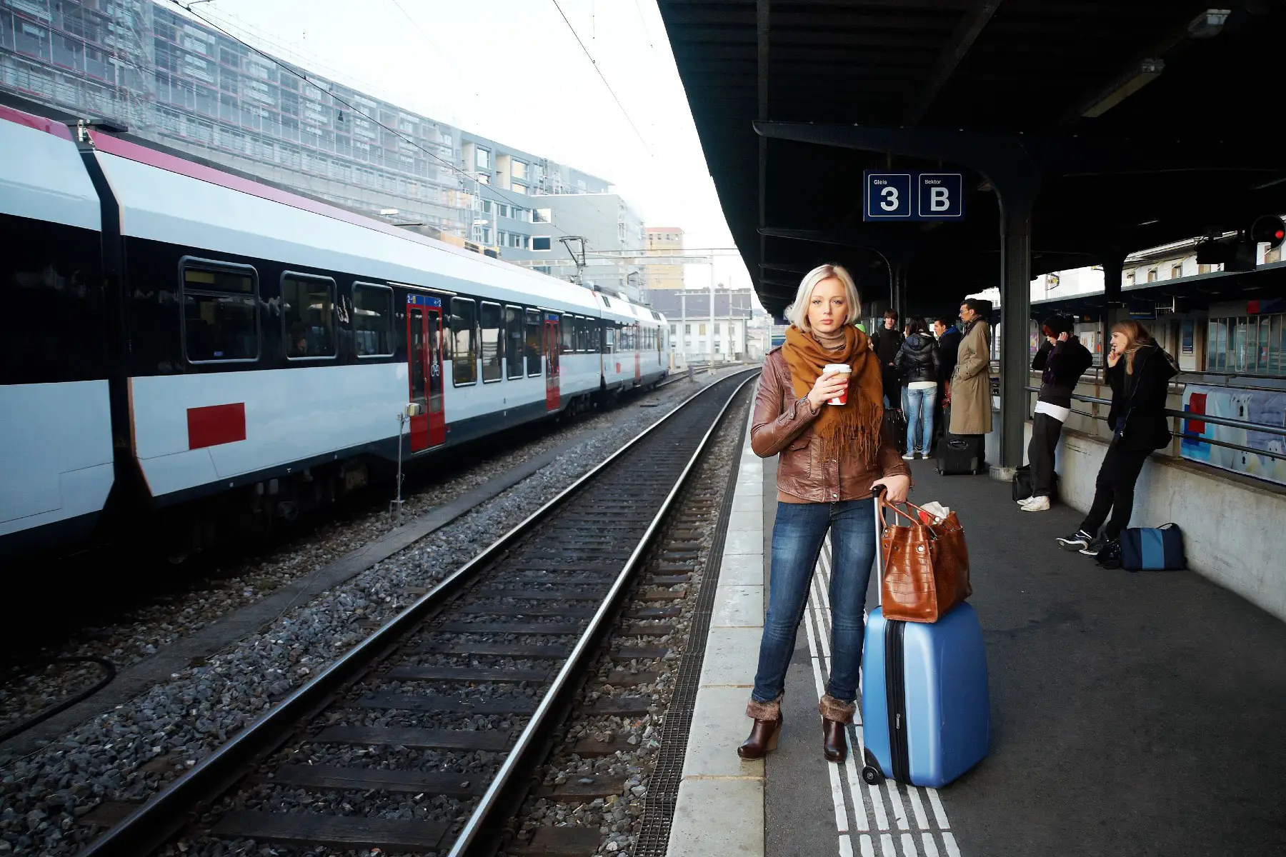Woman with luggage at train station, train travel Switzerland