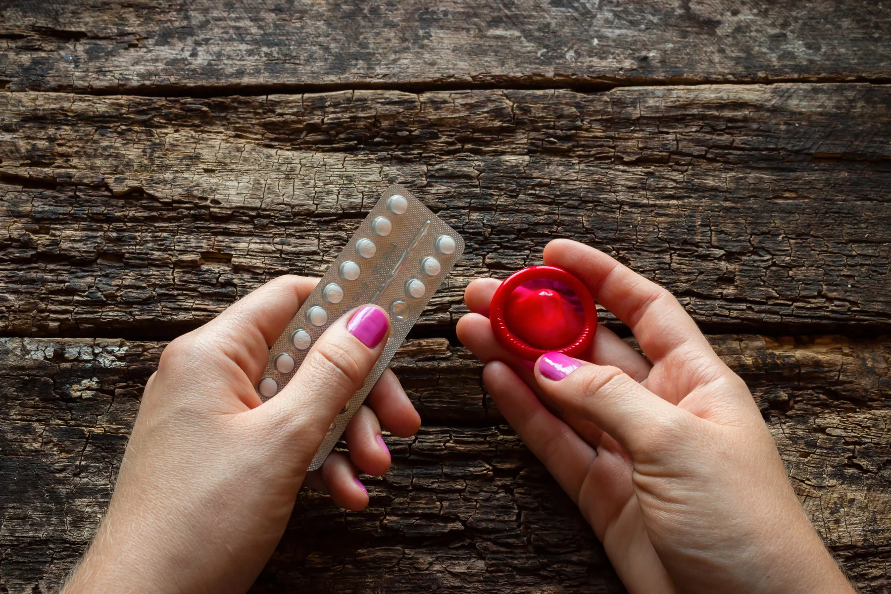 contraception: a woman holding two forms of birth control, a condom and the pill
