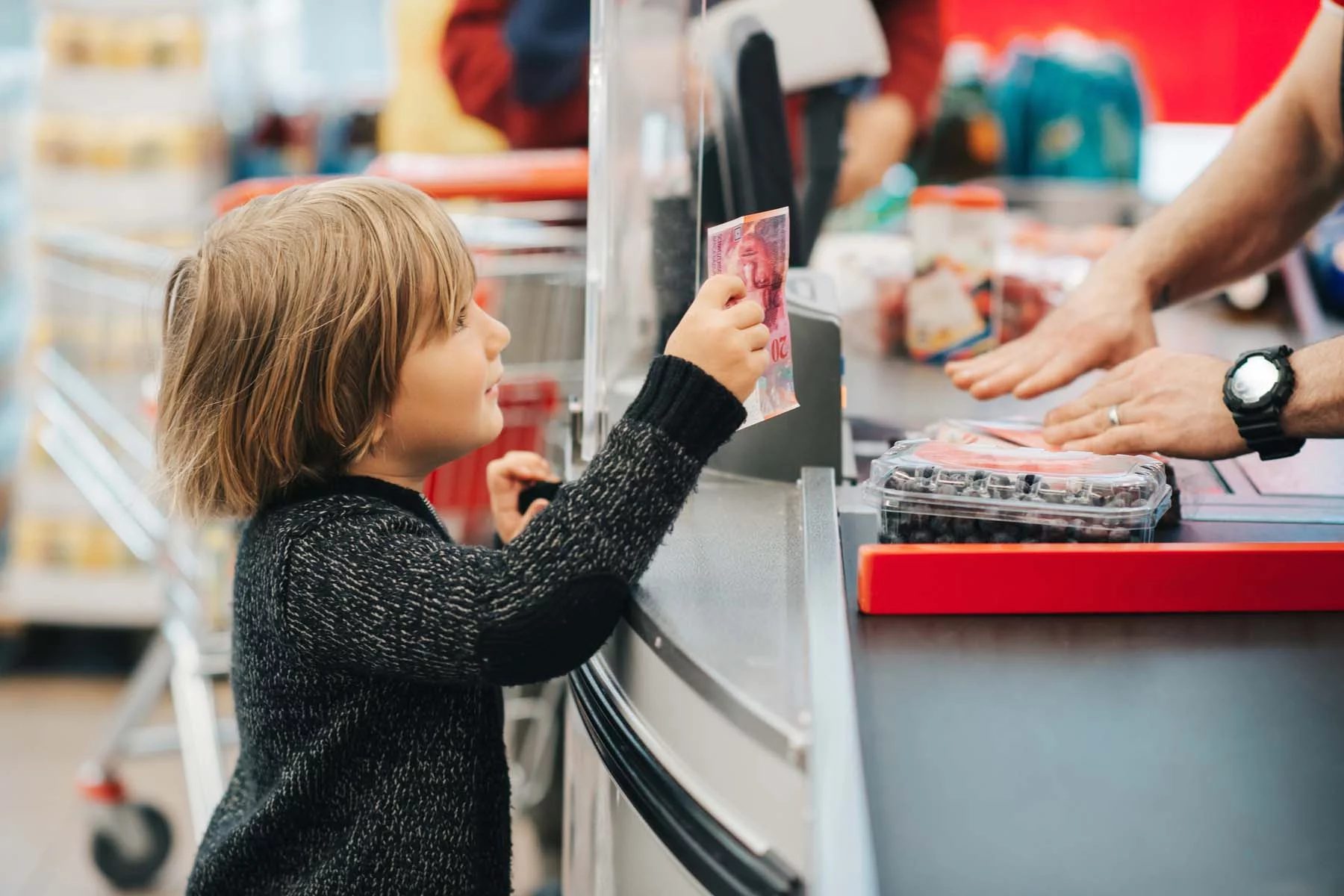 Boy paying Swiss supermarket