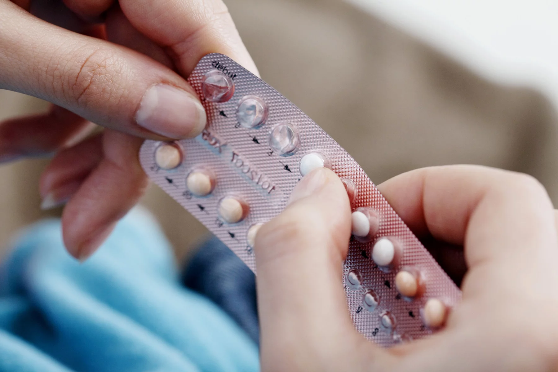 a woman holding a pack of contraceptive pills