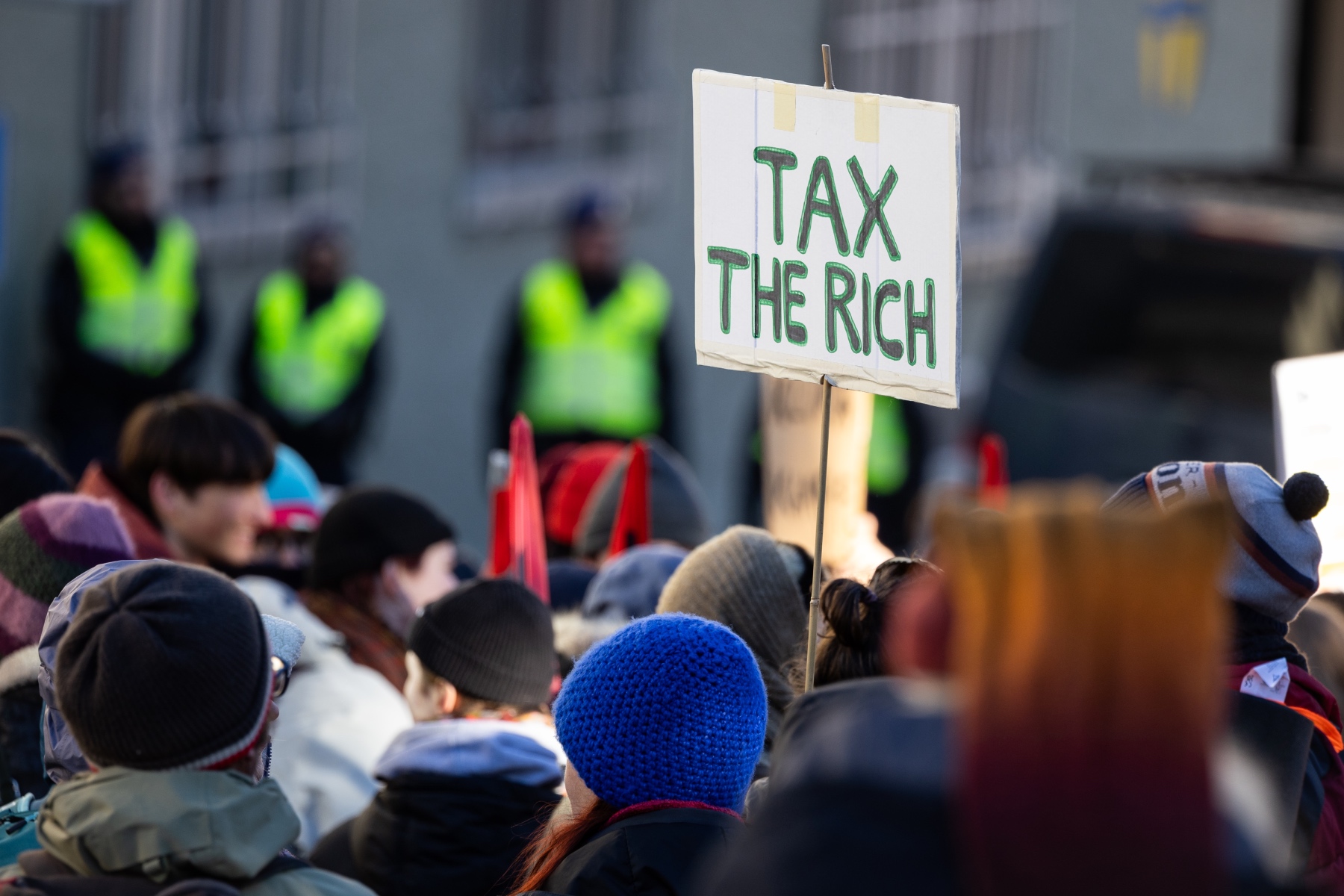 A sign with the text 'Tax the rich' is raised at a protest for environment justice in Davos on 14 January 2024 against the World Economic Forum 