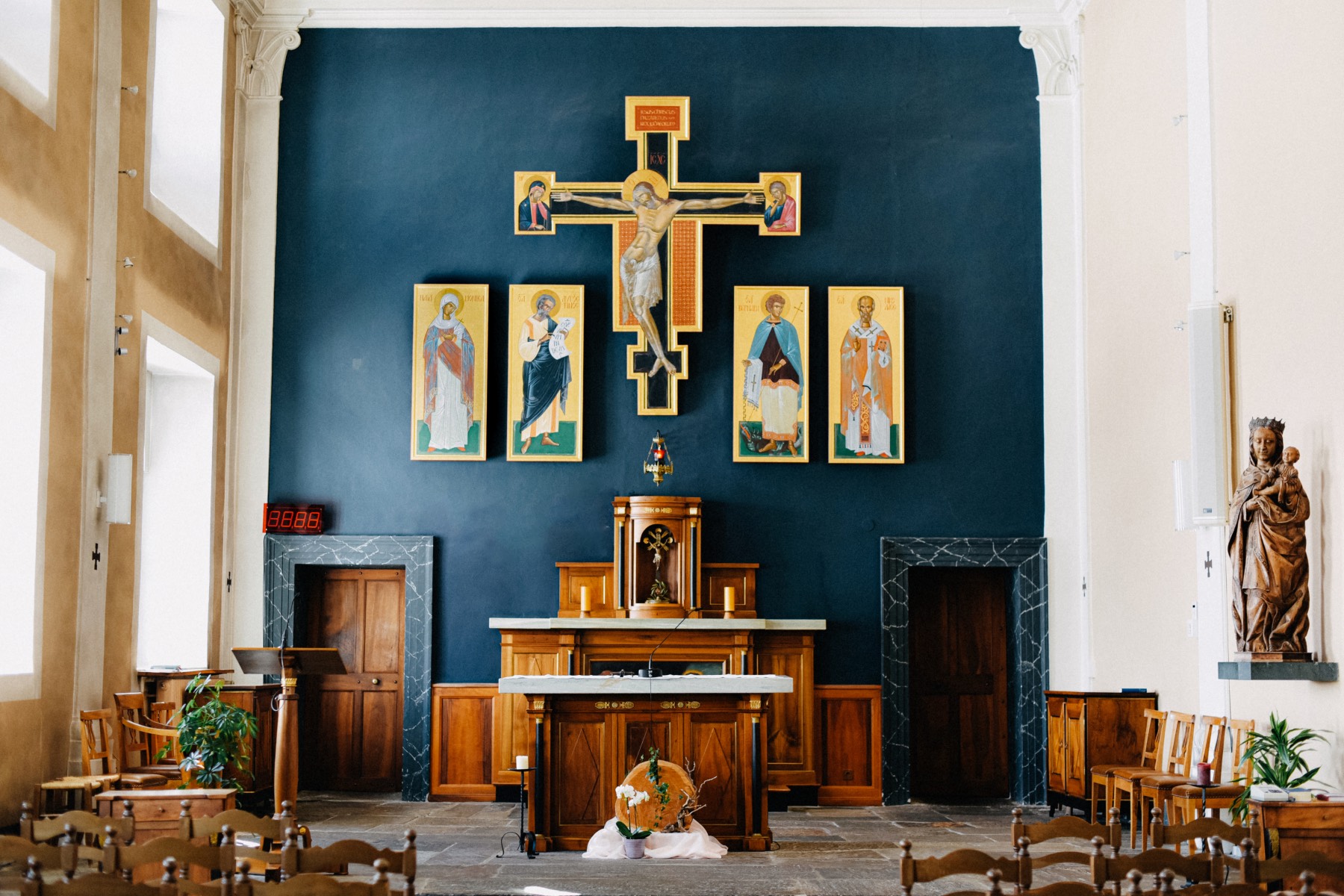 A chapel interior with a wooden altar and Medieval style paintings