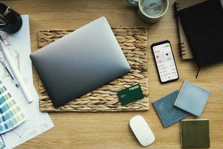 Top-down image of a closed laptop, mouse, phone and various other bits.