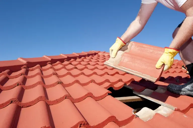 Construction worker putting roofing tiles on top of a house.