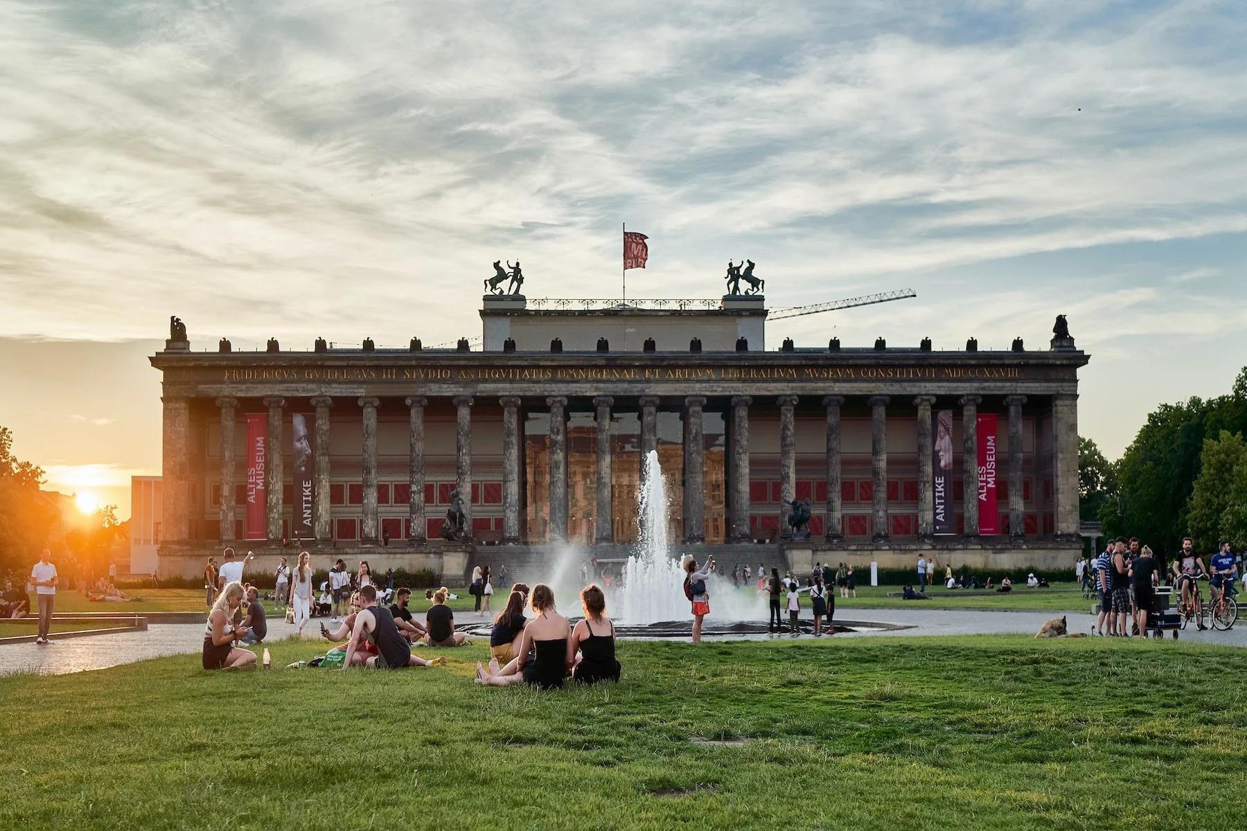 Altes Museum in Berlin at sunset, with many people sitting on the lawn