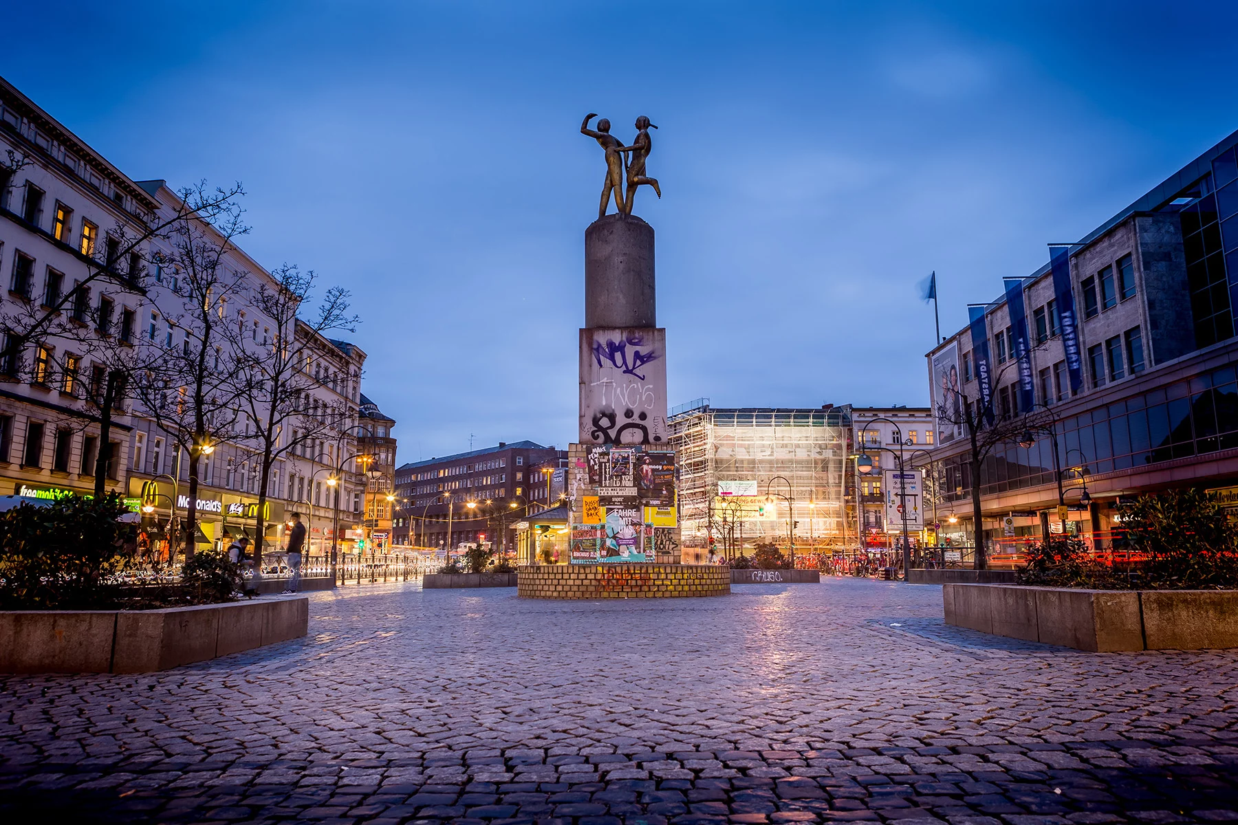 A town square with statues at night in Neuköllln, Berlin