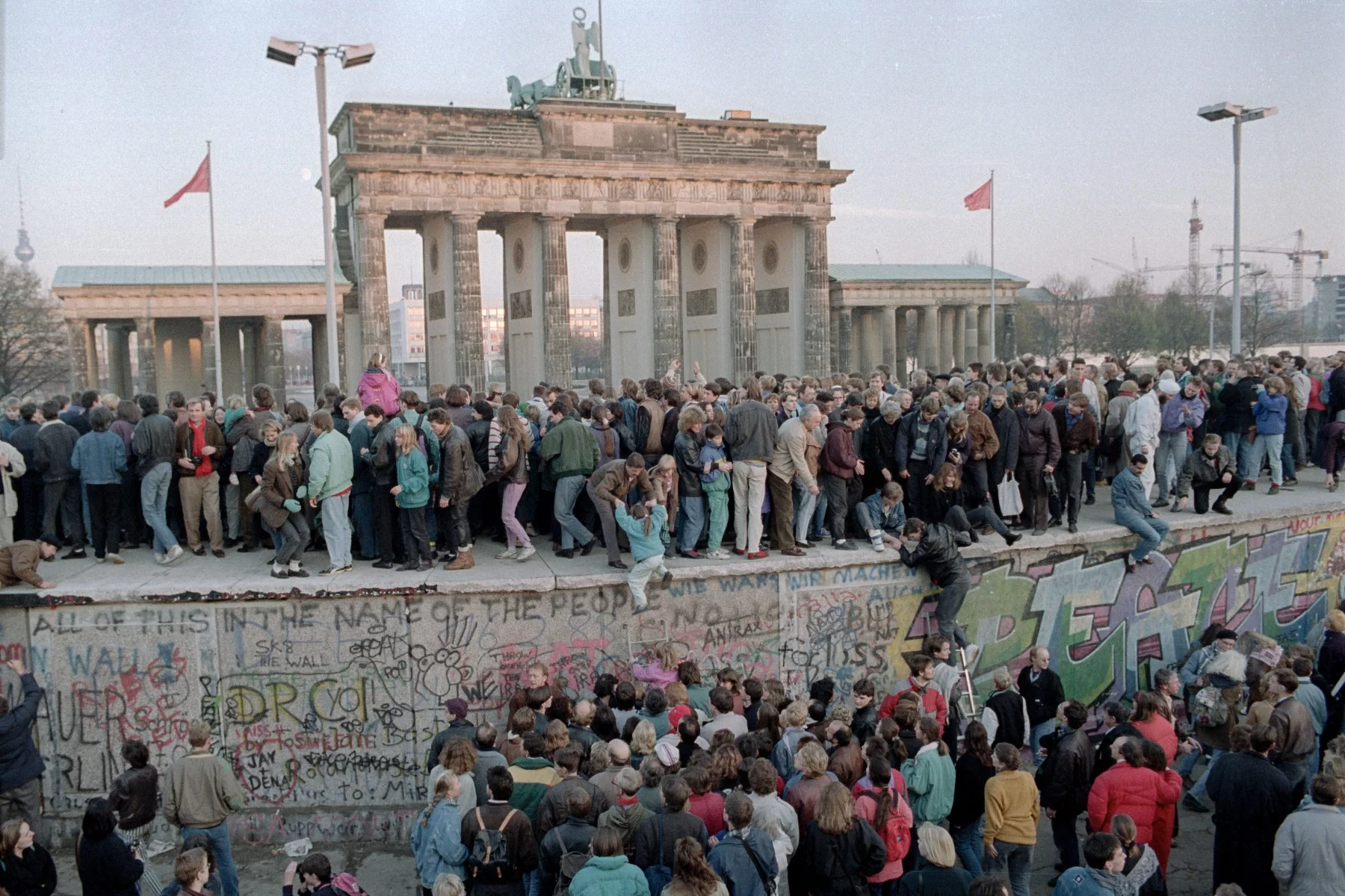 Large crowd standing on the Berlin Wall near the Brandenburg Gate in November 1989.