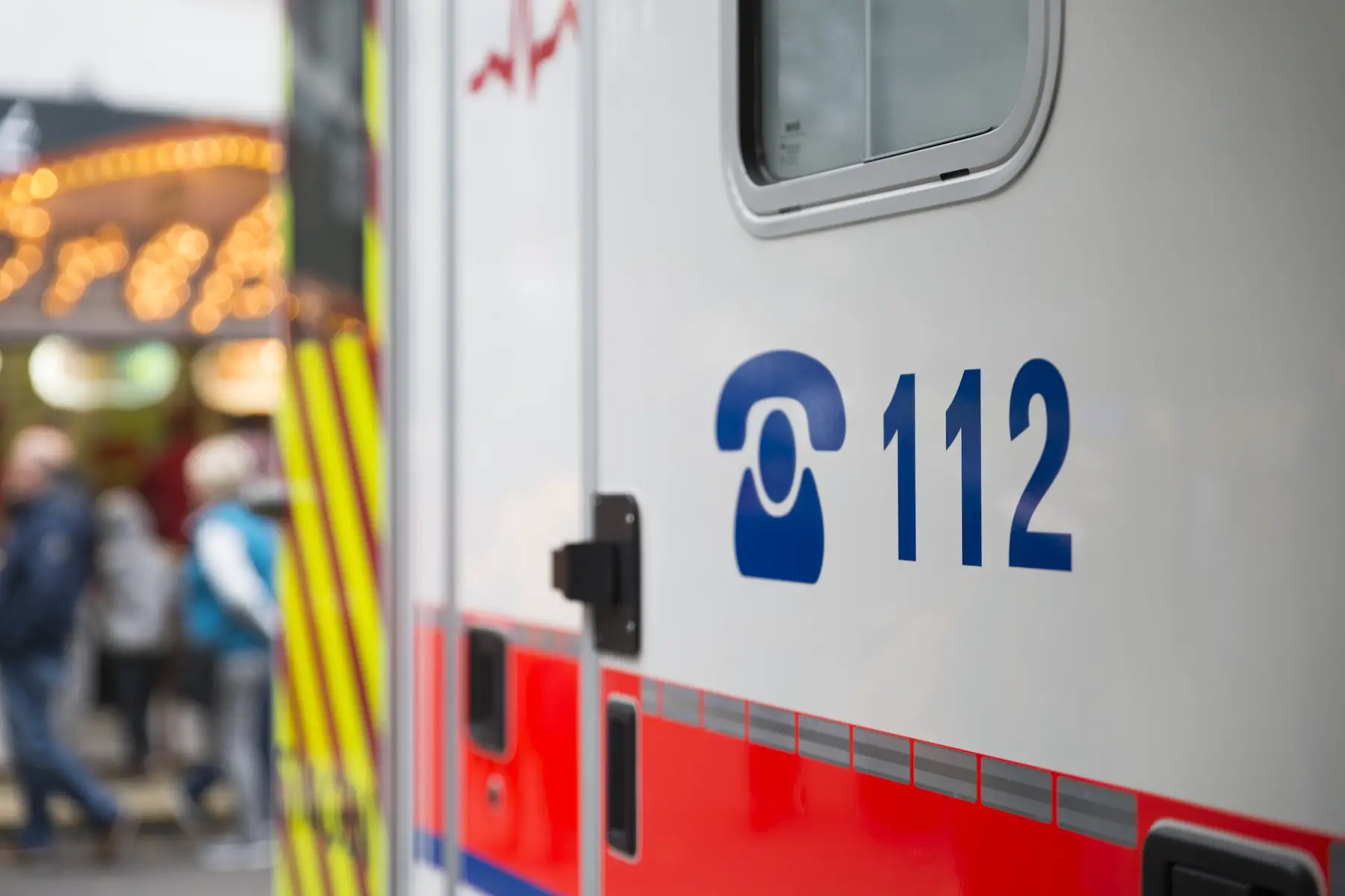 Close-up of a German ambulance parked at a Christmas market, with the emergency number 112 displayed on the vehicle's side