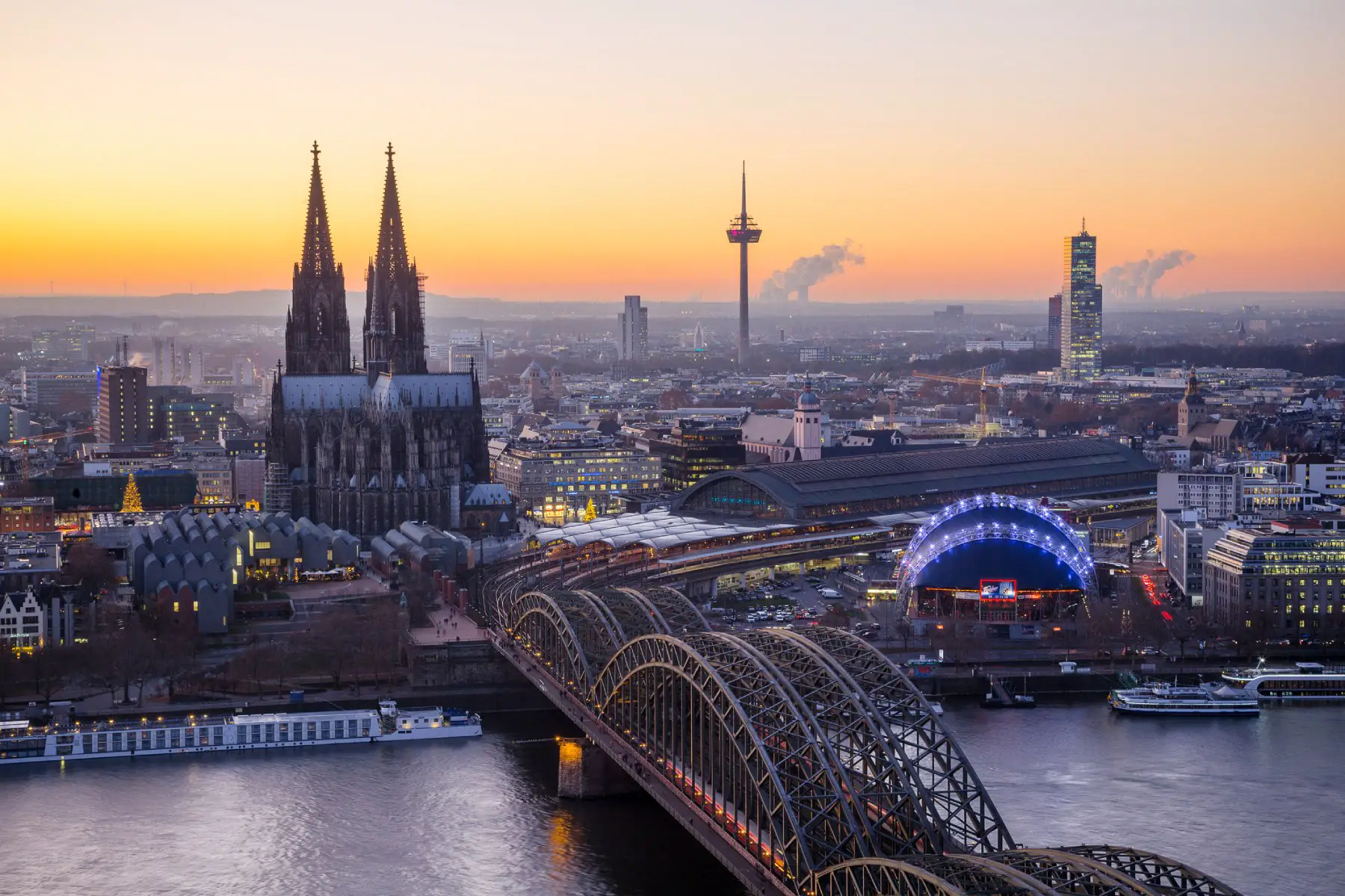 the sun setting over Cologne Cathedral and Hohenzollern Bridge