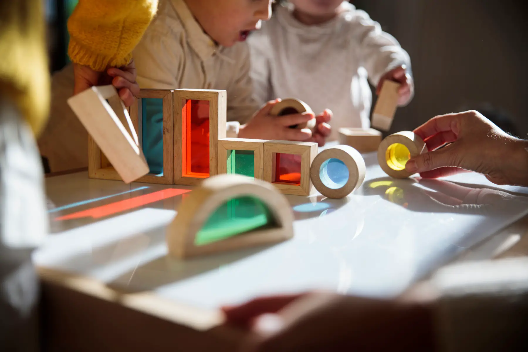 little children playing with colorful wooden building blocks on a table